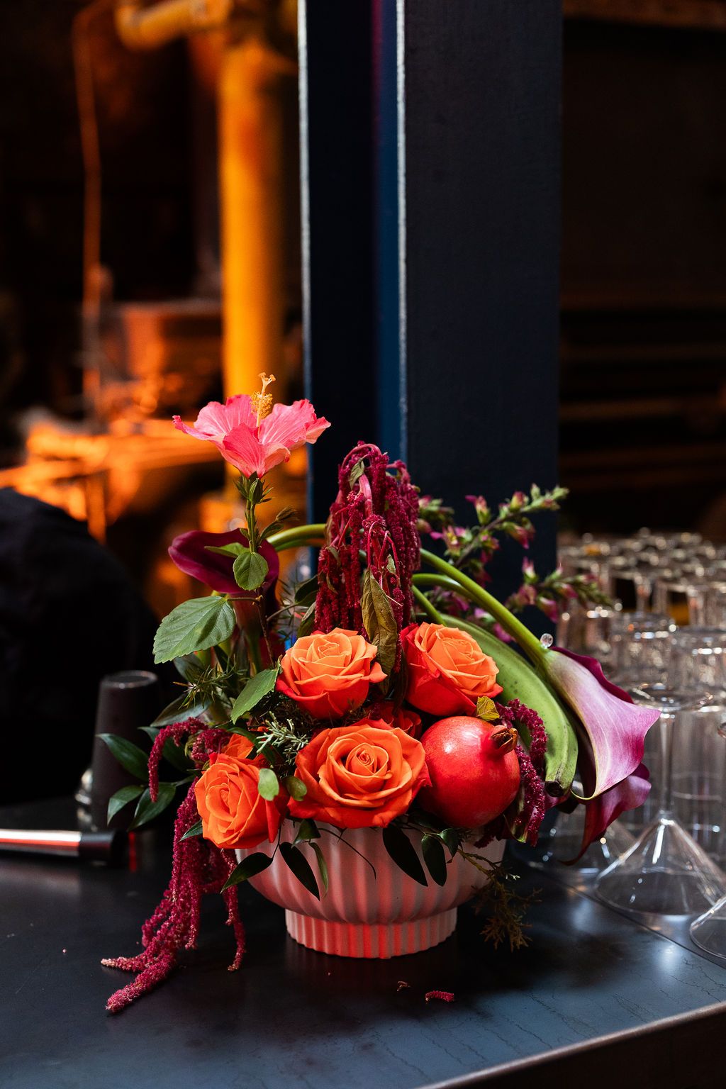 Vibrant floral centerpiece with orange roses and red amaranth at a wedding reception.