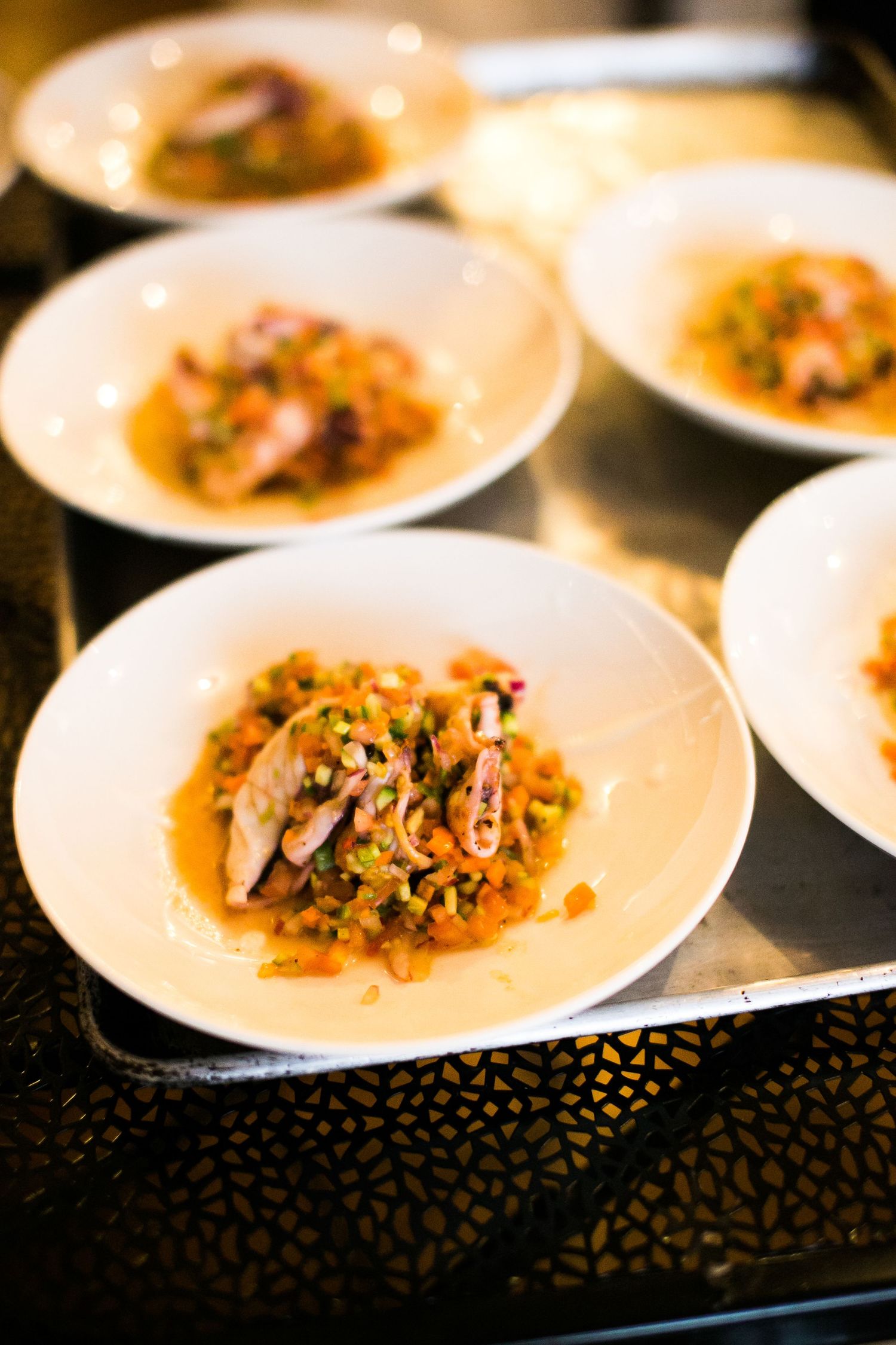 Elegant plated seafood appetizers with rice and shrimp served on white dishes at wedding catering event.