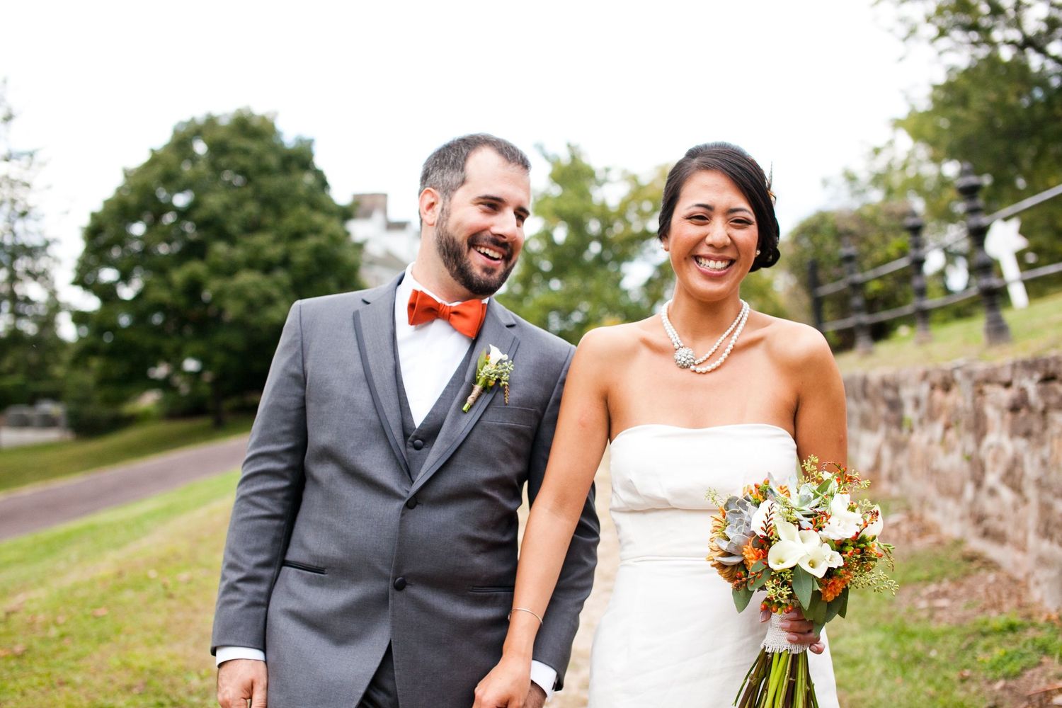 Smiling bride and groom walking outdoors on their wedding day together.