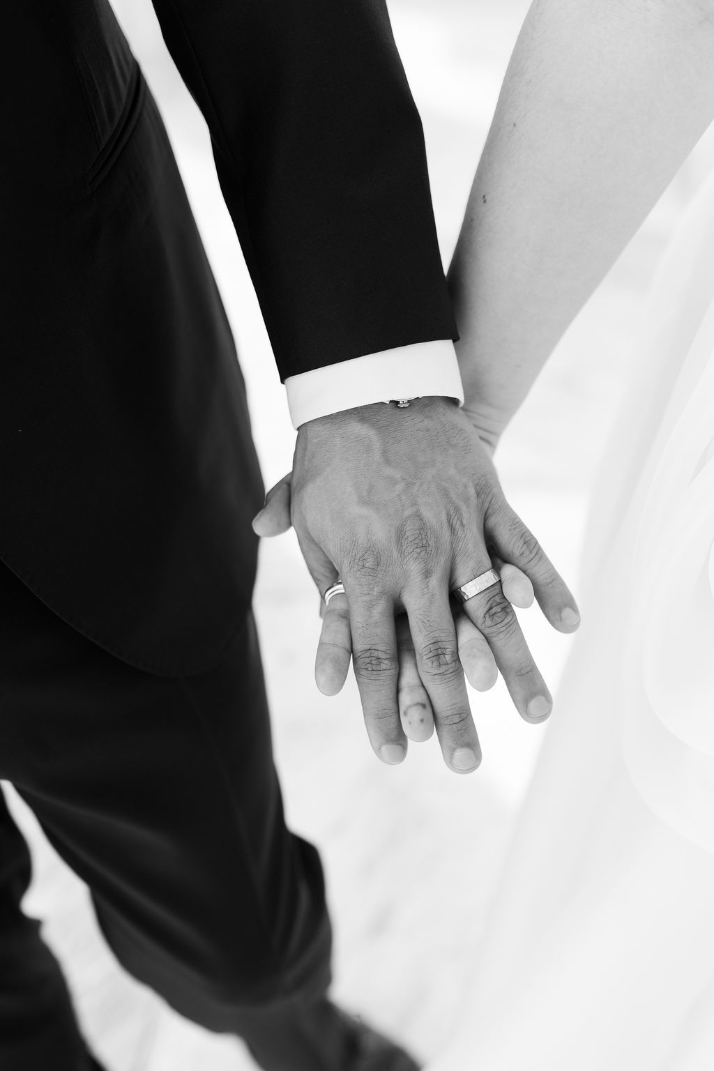 Close-up black and white photo of newlyweds hands showing wedding bands after their marriage ceremony.