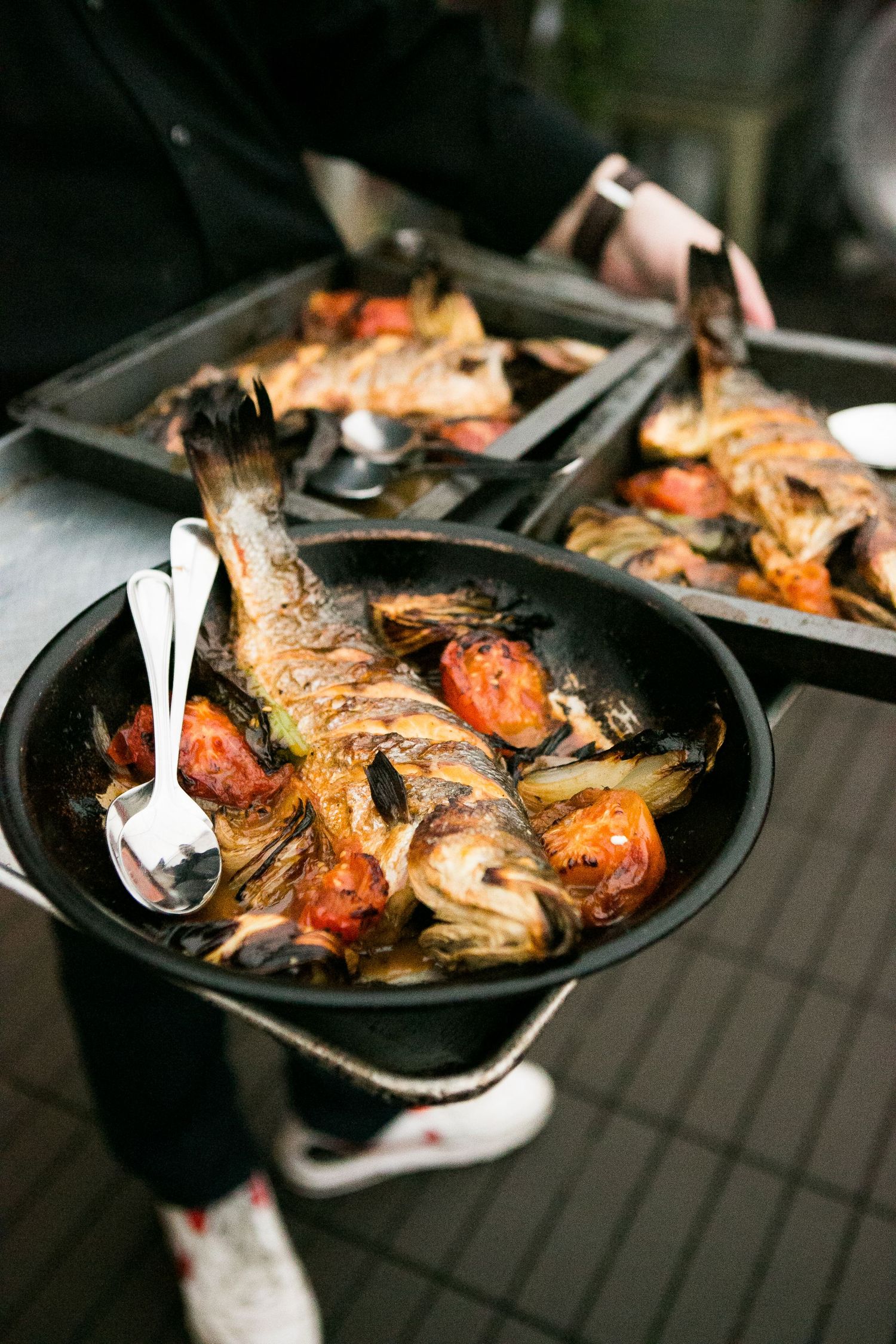 Roasted whole fish with tomatoes served in cast iron pan at wedding.