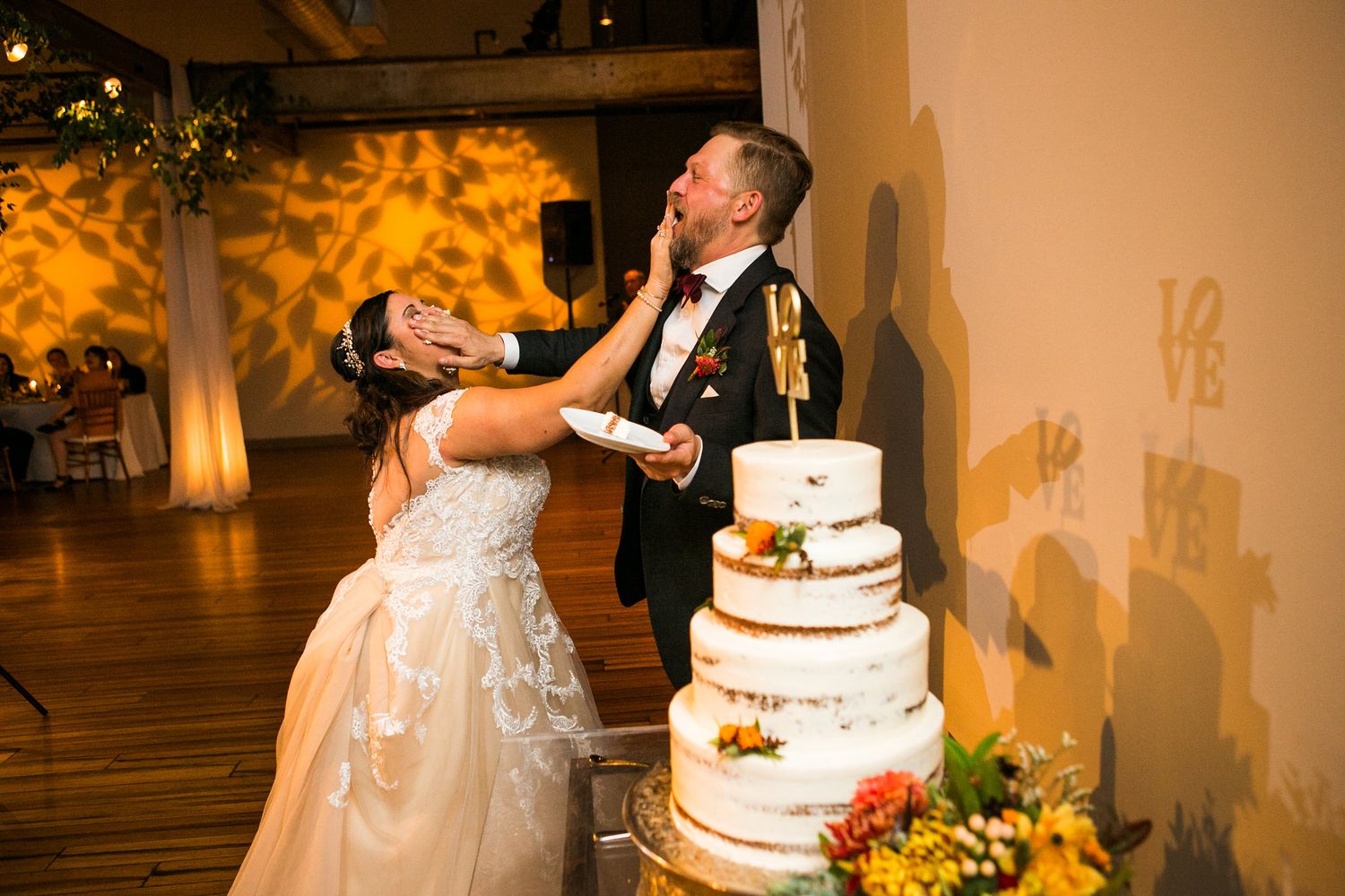 Bride playfully feeds groom wedding cake during fun reception celebration moment.