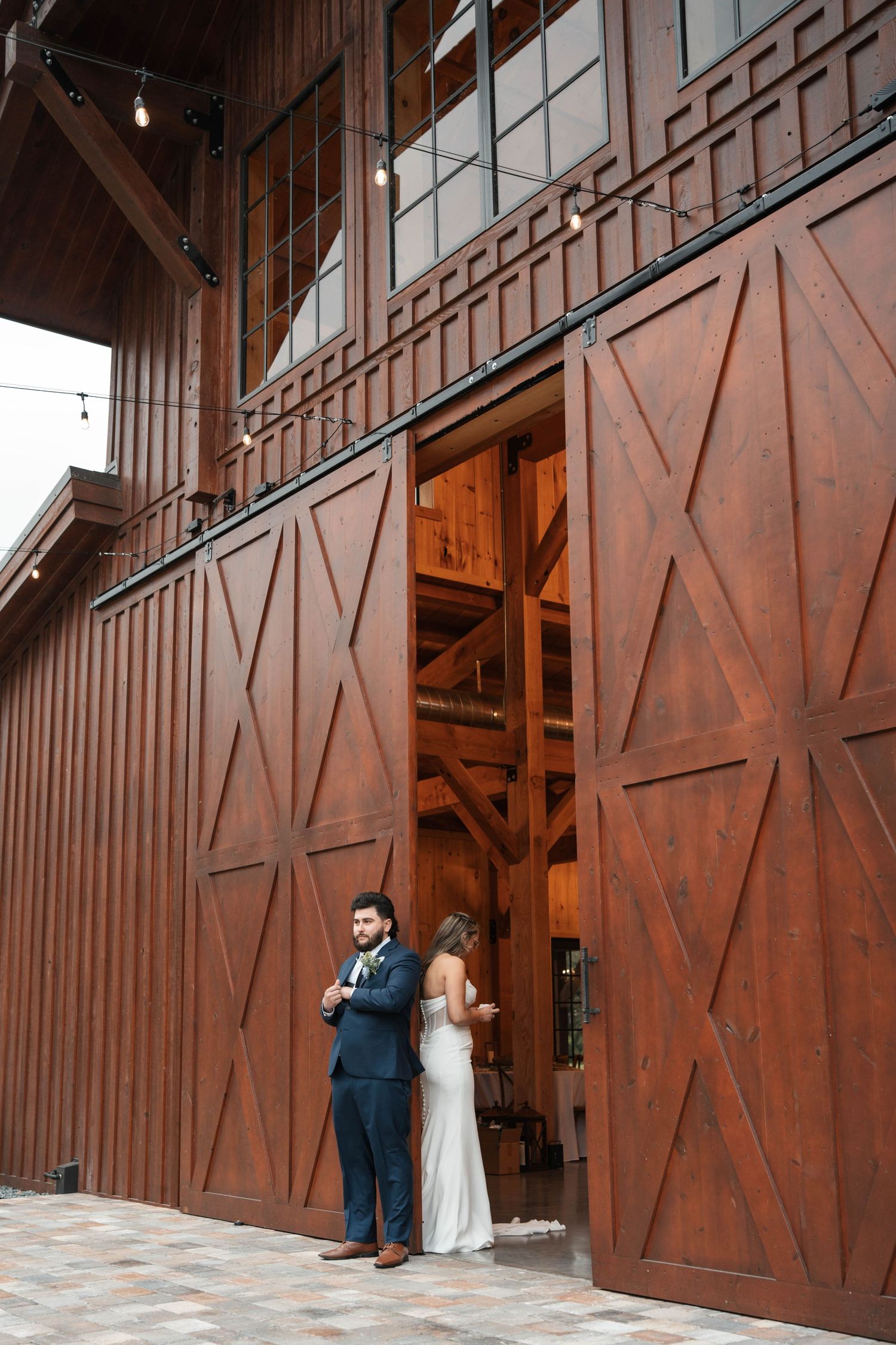 Bride and groom share first look moment at rustic barn wedding venue with large wooden sliding doors.