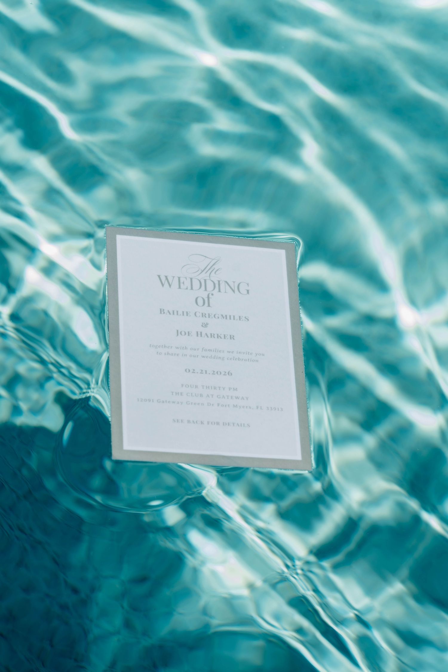 Elegant wedding invitation for Bailie Creighley and Joe Harker floating in a turquoise blue pool.