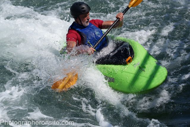 This is the strong action shot of a kayaker navigating whitewater rapids.