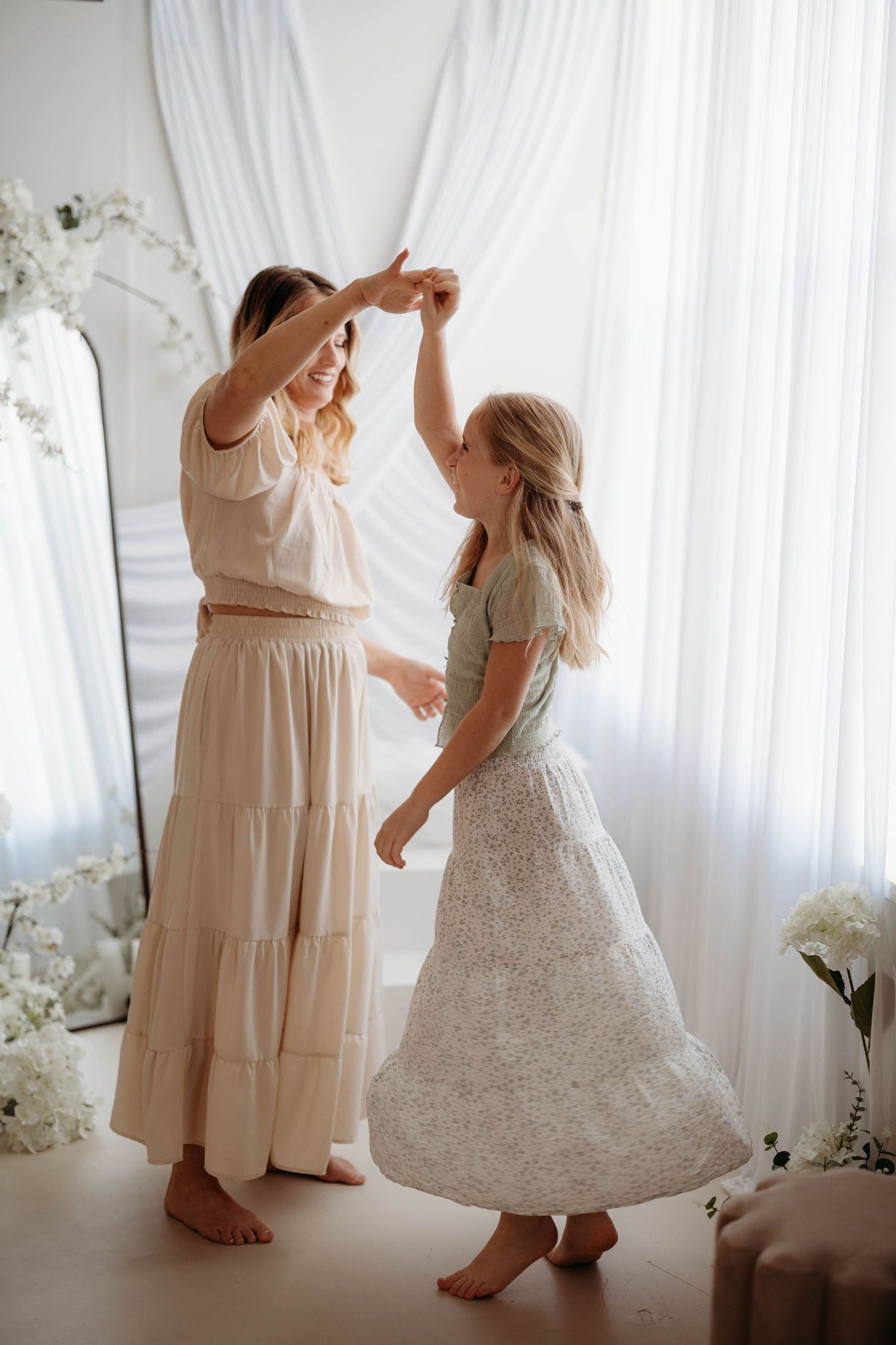 Mother and daughter dancing together barefoot in white floral studio with mirror and draping. Motherhood  in west lafayette indiana