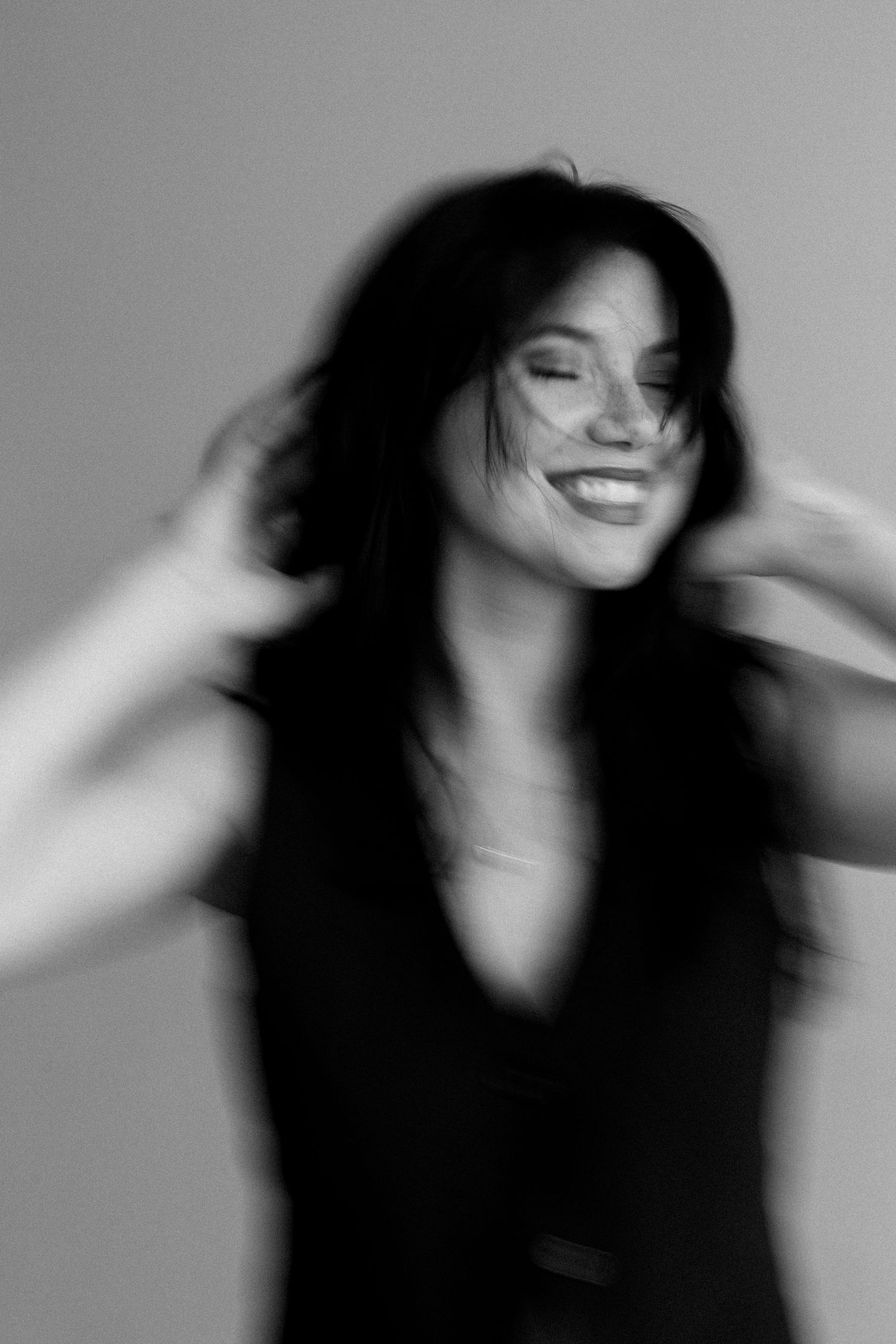 Blurred black and white portrait of joyful dark-haired woman smiling with hands in hair. Lafayette indiana tippecanoe county west lafayette