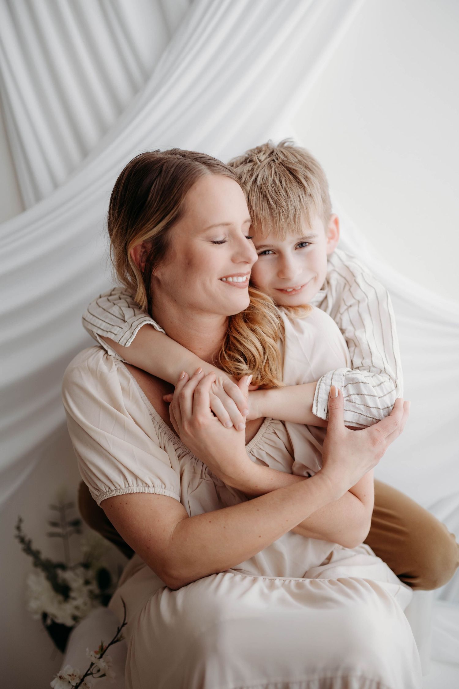 A smiling mother embraces her young blonde son against a soft white backdrop. Lafayette indiana tippecanoe county west lafayette