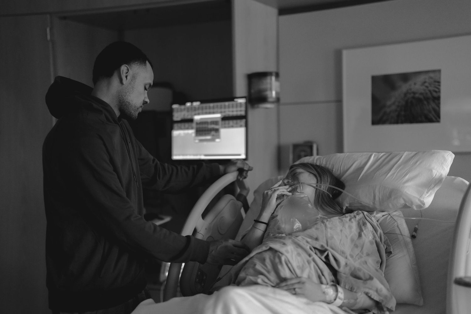 A black and white photo of a man comforting a woman in a hospital bed during labor. Lafayette indiana tippecanoe county west lafayette
