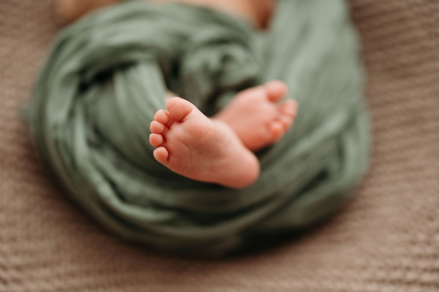 Close-up of newborn baby feet wrapped in soft sage green swaddle blanket. Lafayette indiana tippecanoe county west lafayette