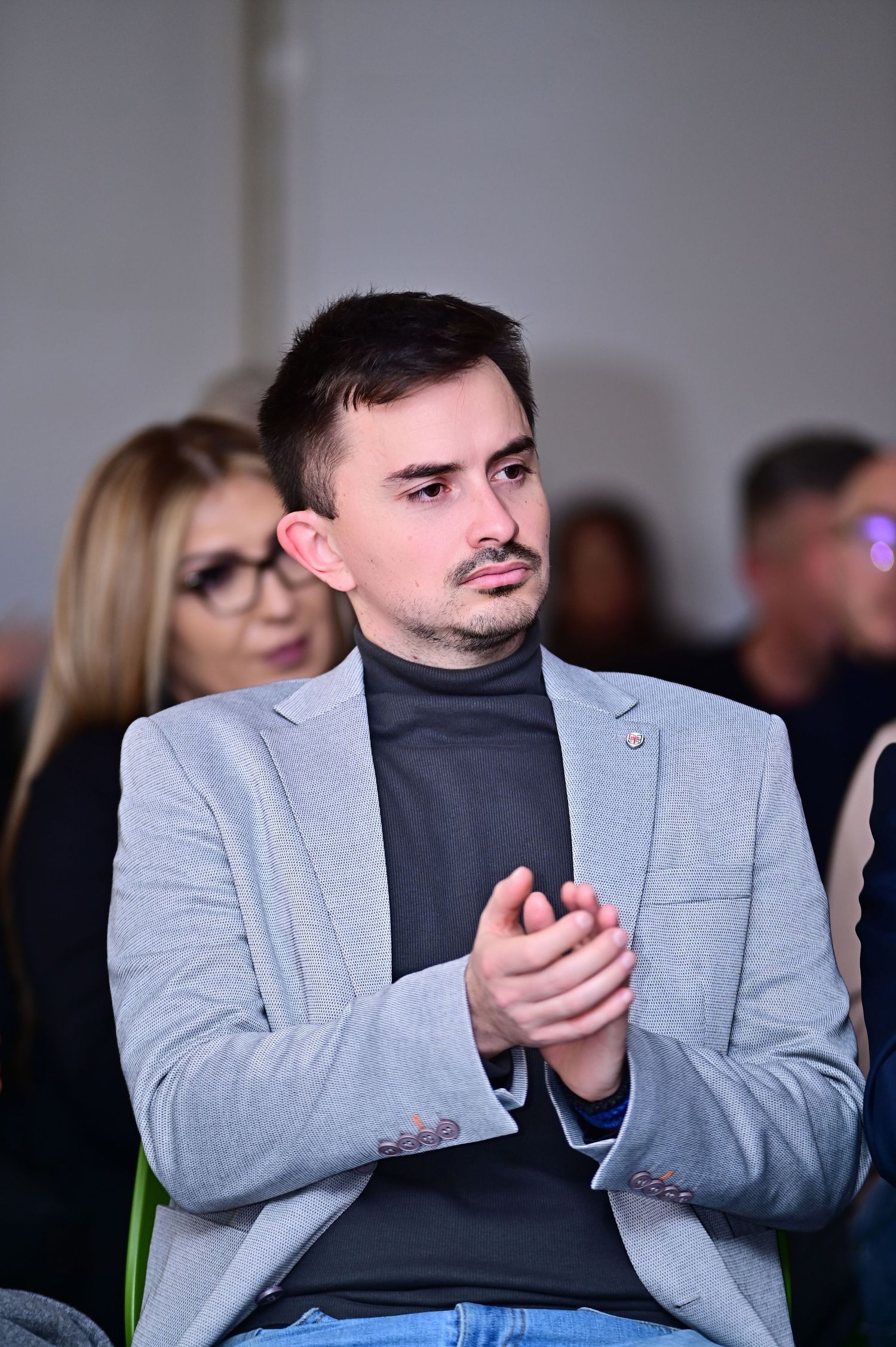 Professional woman in a white blazer attending a business conference, corporate event, or leadership seminar, listening attentively