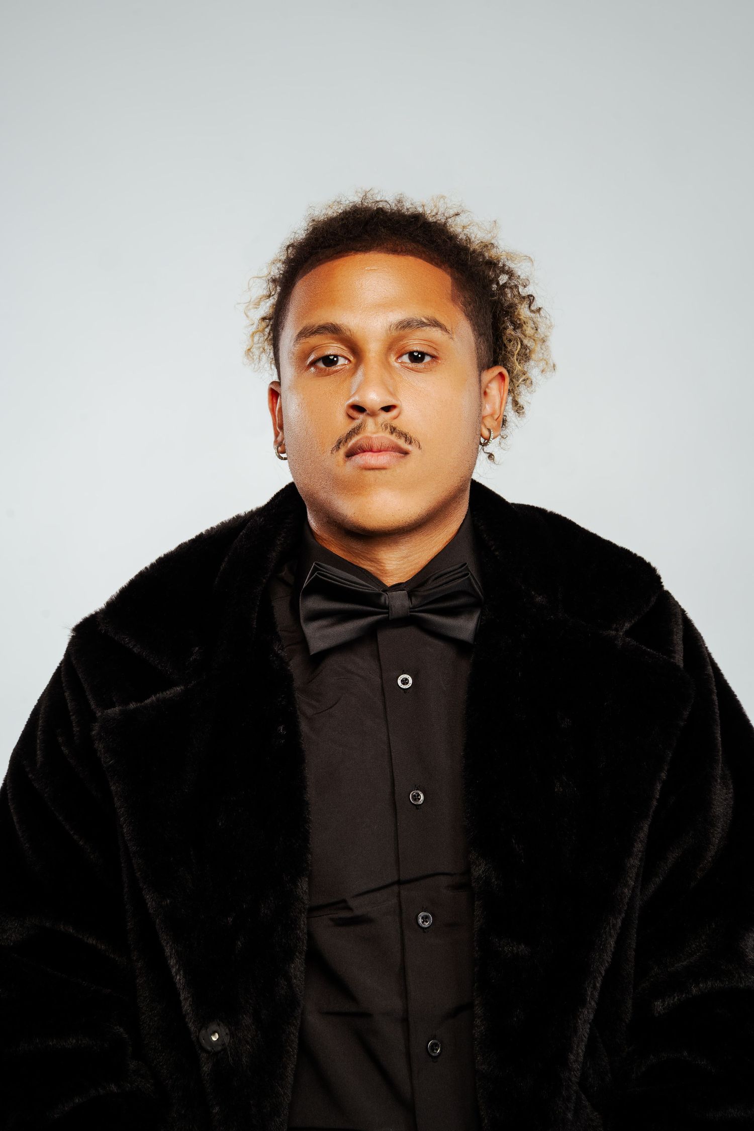Young man in black velvet coat and bow tie posing for a formal portrait.