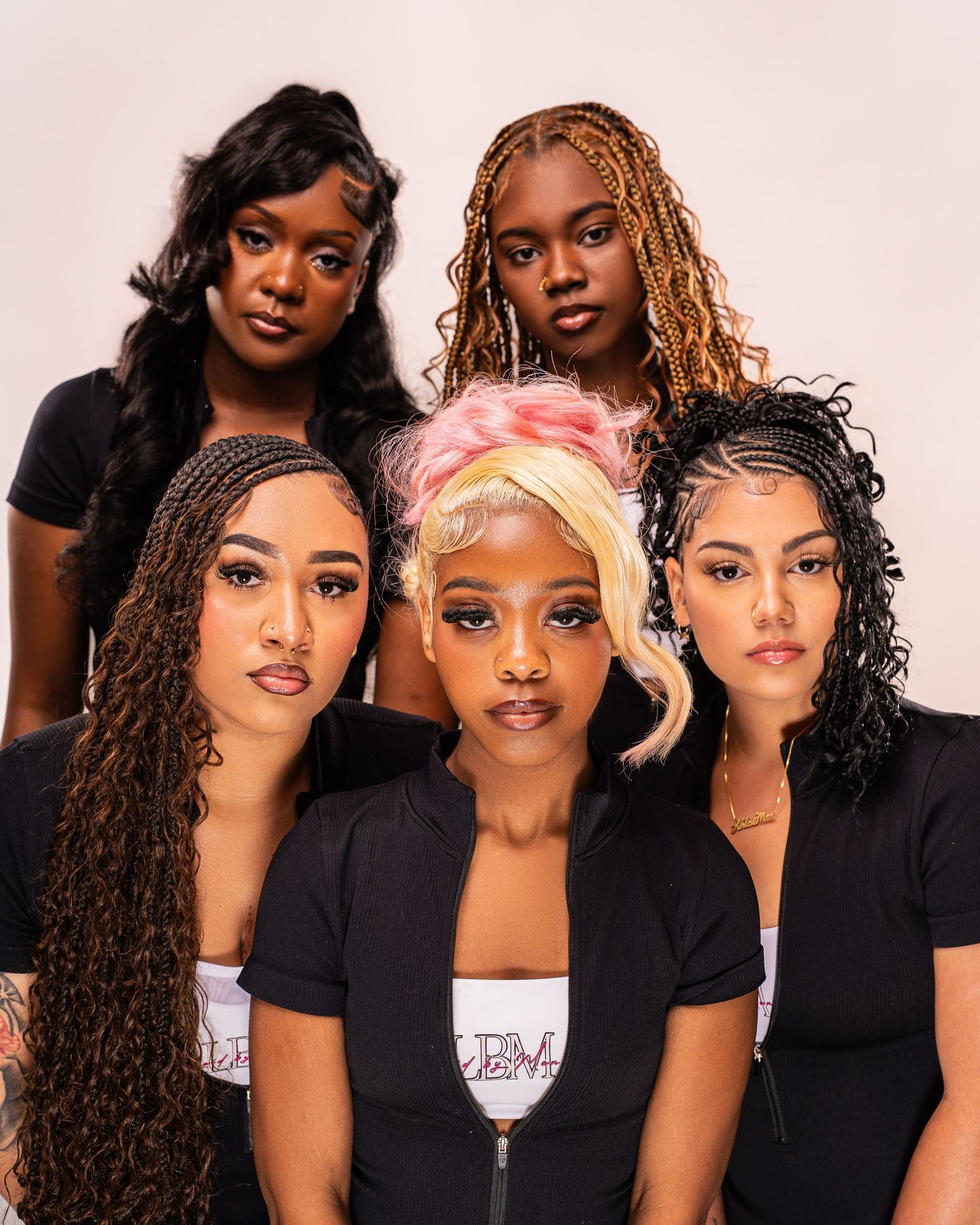Five women with diverse natural hairstyles pose together wearing black LBM branded shirts.