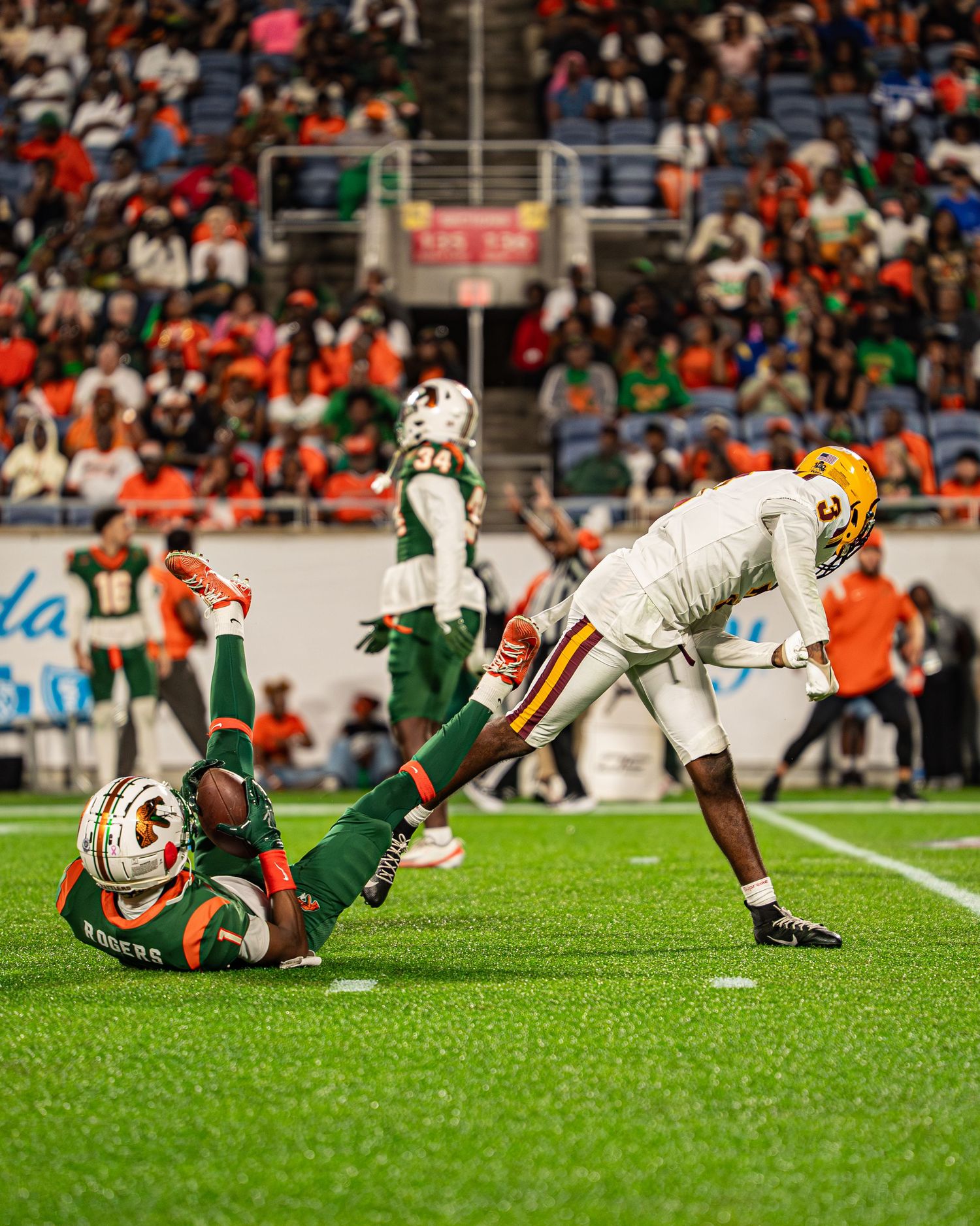 Bethune-Cookman player stands over a fallen FAMU opponent during an intense college football game.