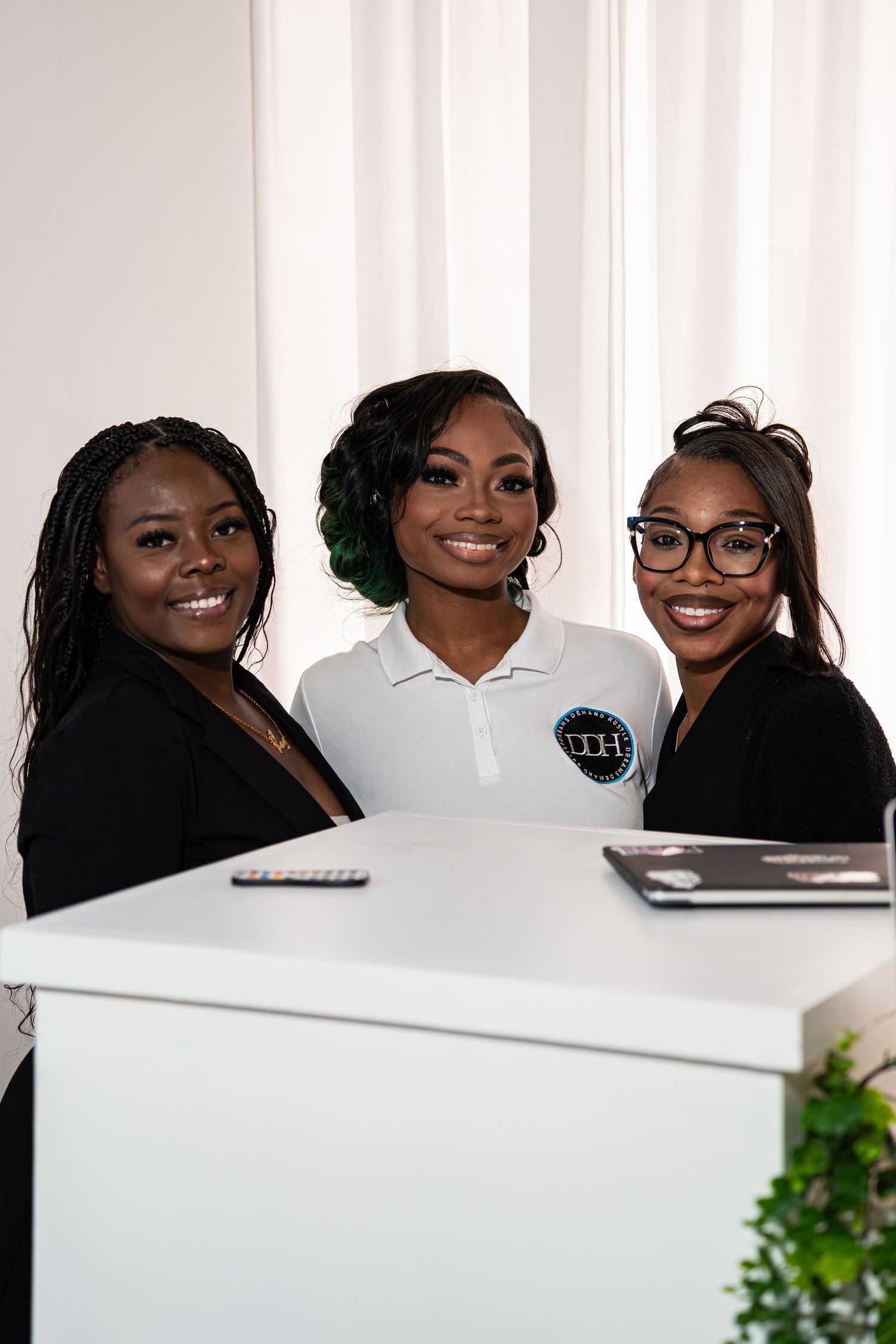 Three smiling women pose at DDH reception desk at entrepreneur networking event.