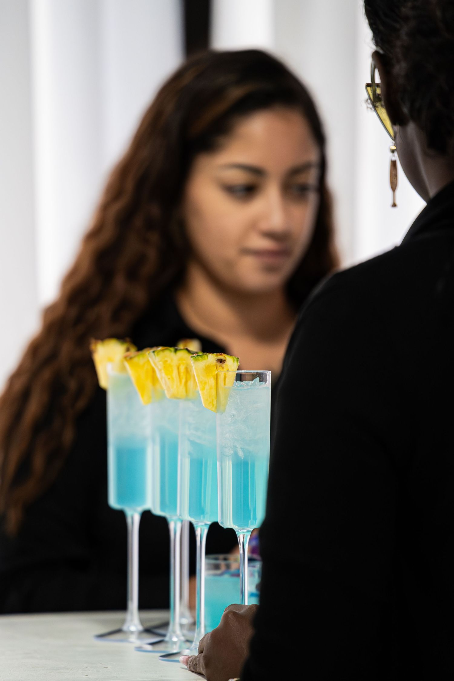 Blue tropical cocktails garnished with pineapple served at elegant event bar.