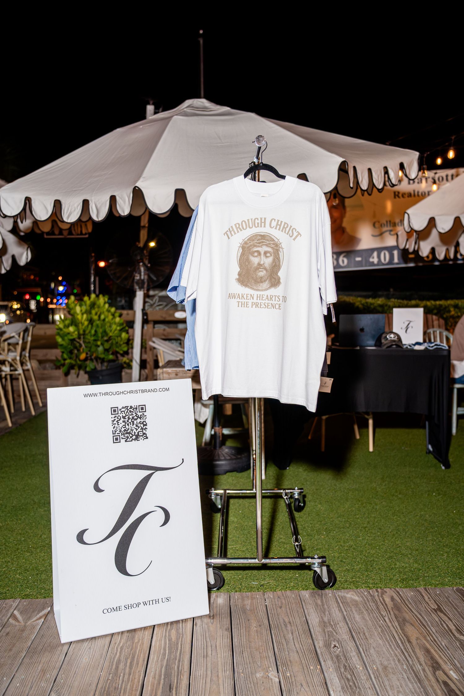 Through Christ Brand white t-shirt with Jesus graphic on display at outdoor night event.