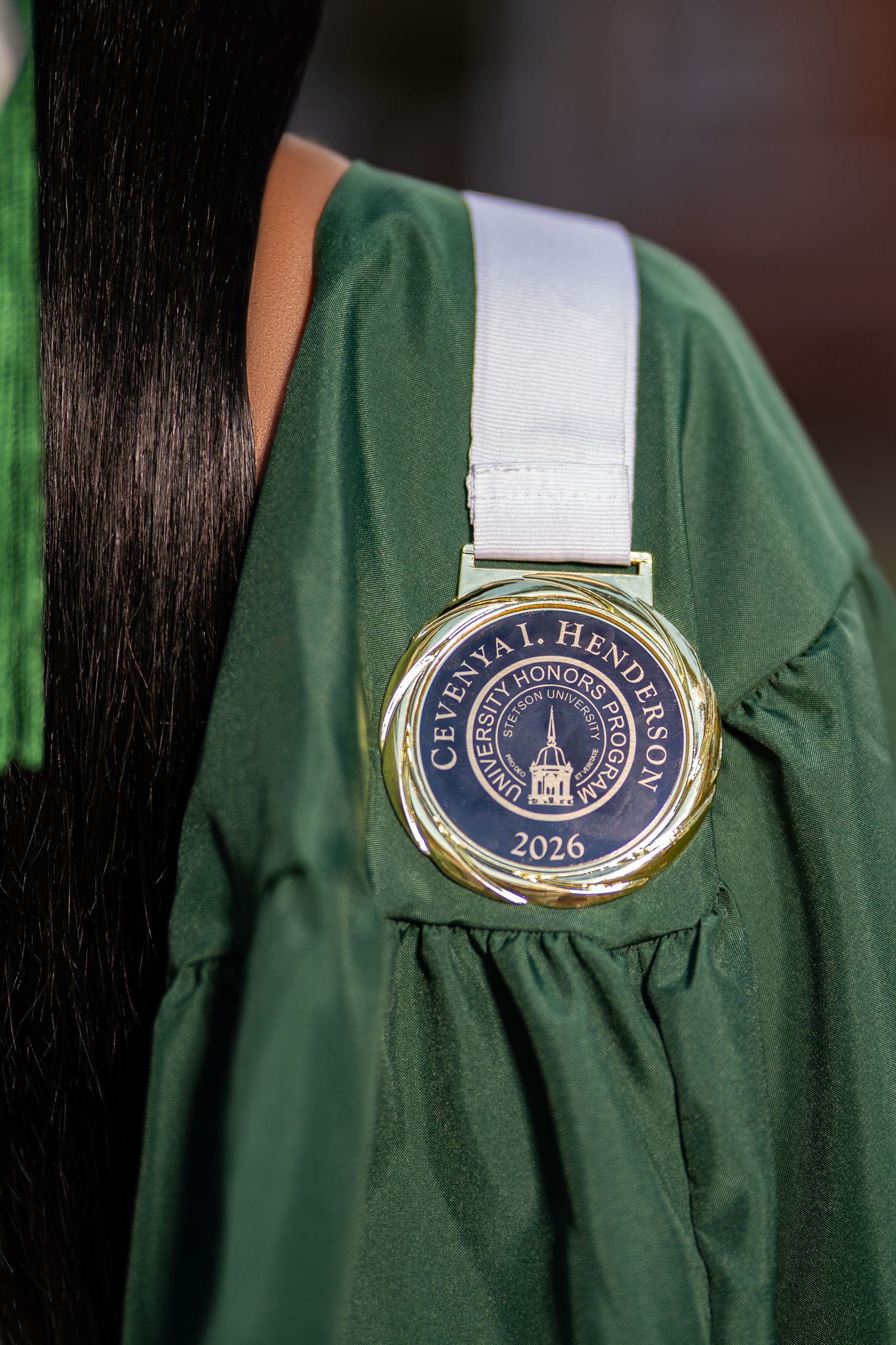 Close-up of University Honors Program medallion for Cevesya I. Henderson, class of 2026, on green gown.