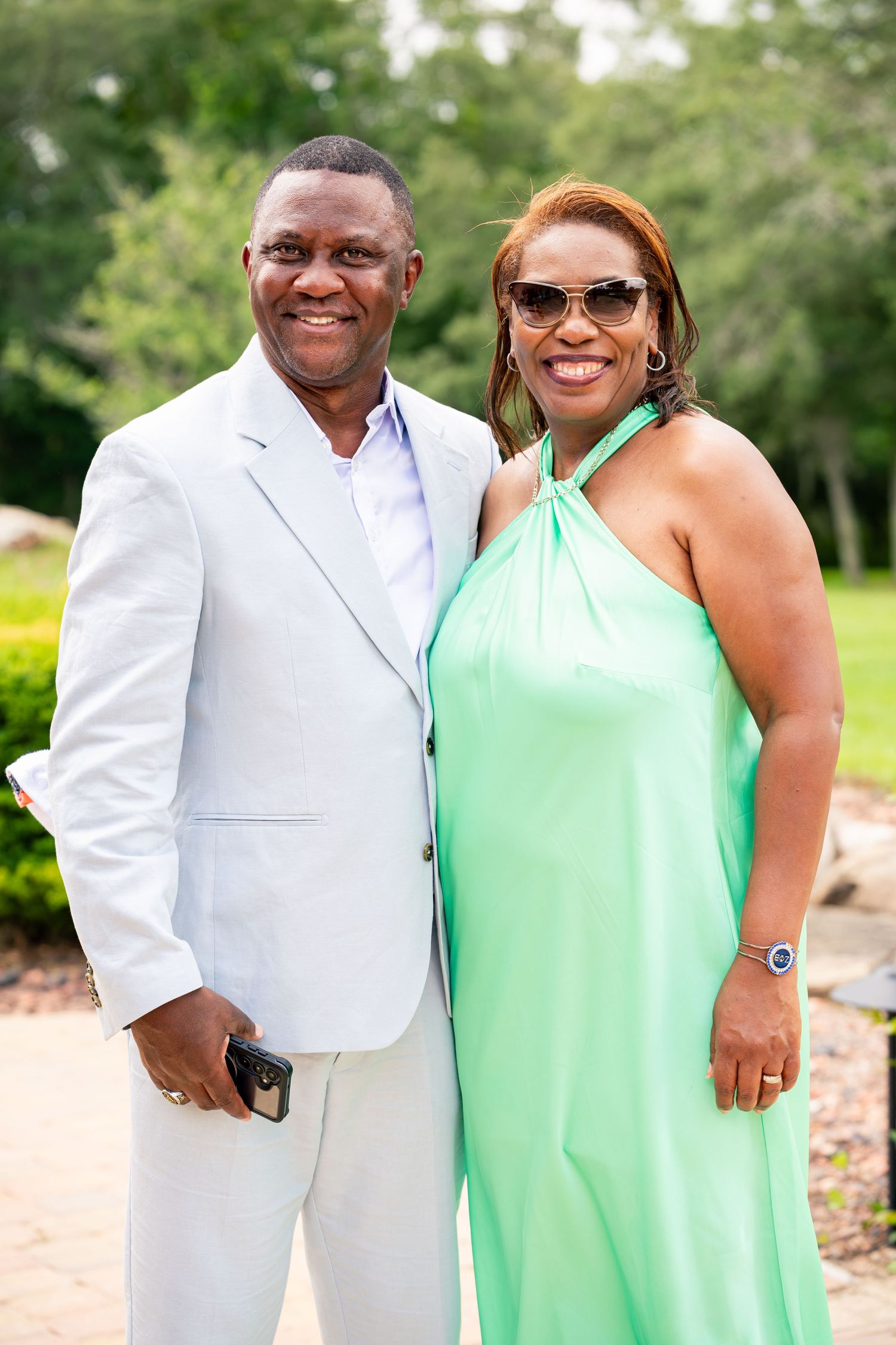 Couple poses together outdoors, man in light gray suit, woman in mint green halter dress.