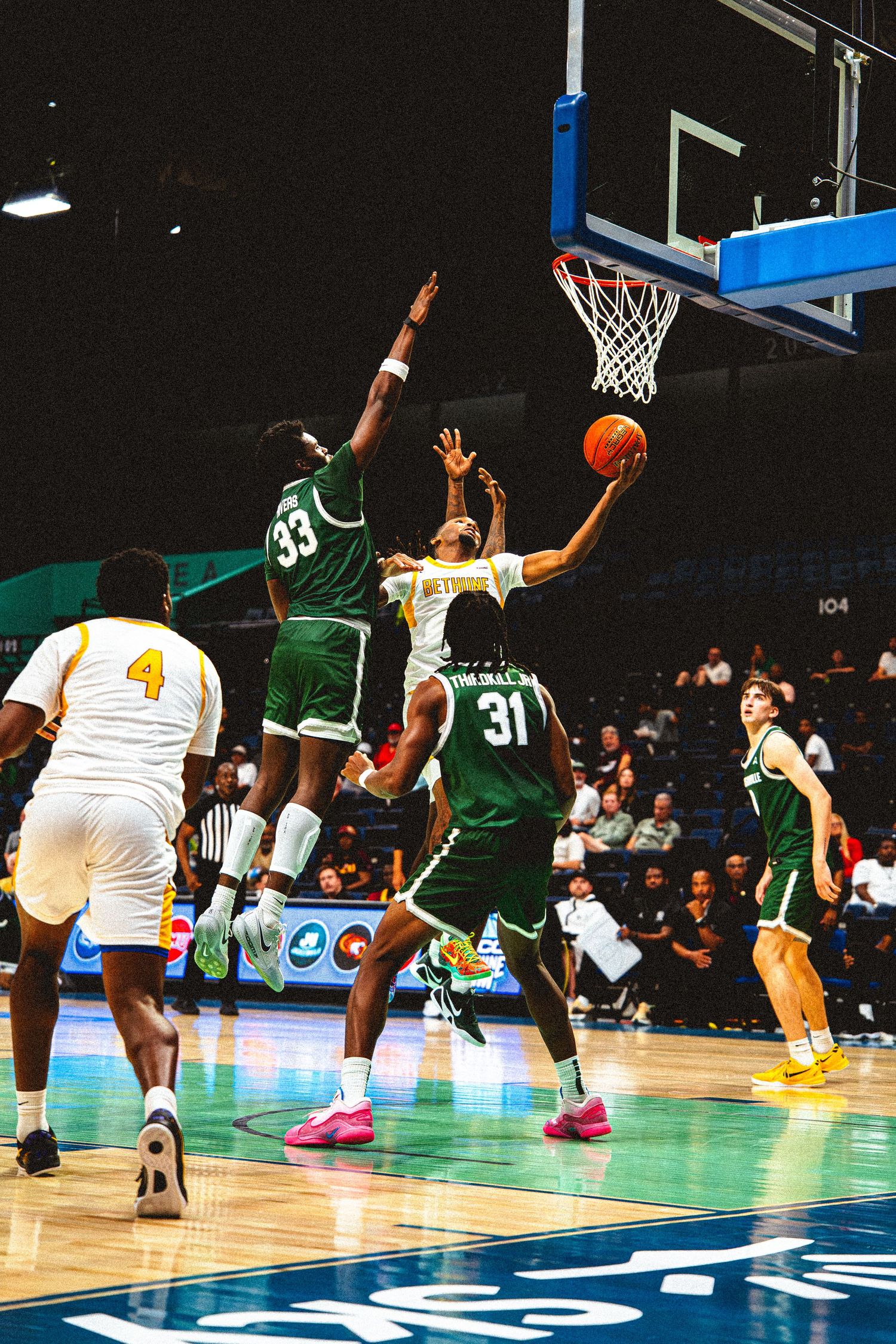 Bethune-Cookman player drives to the basket against Jacksonville University defenders #33 and #31.