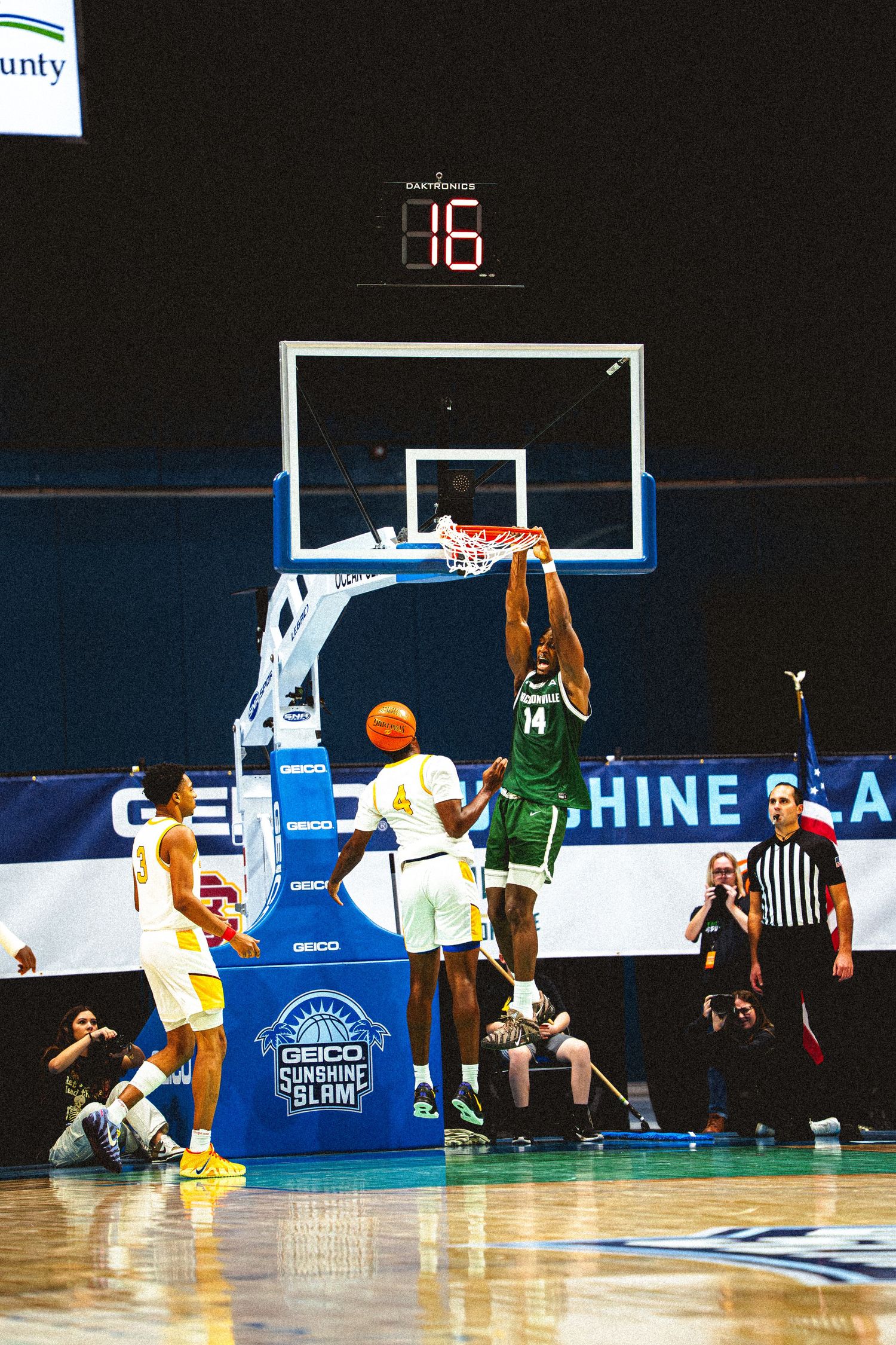 Player #14 in green dunks the ball during the GEICO Sunshine Slam basketball tournament.