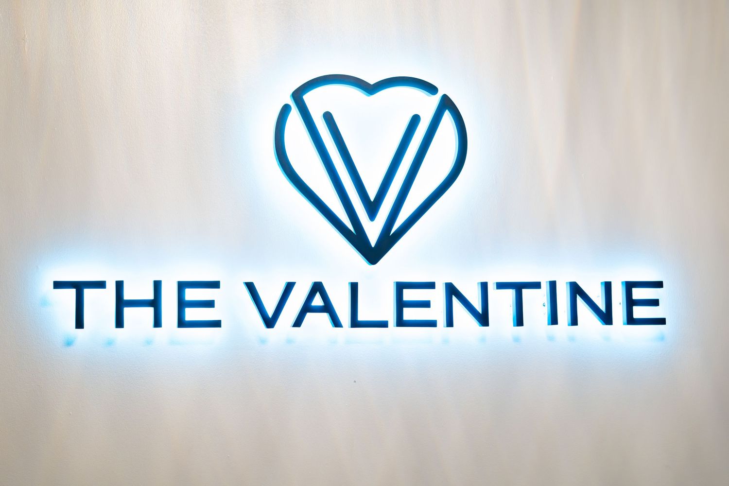 The Valentine event venue logo with illuminated heart design on a modern backlit wall.