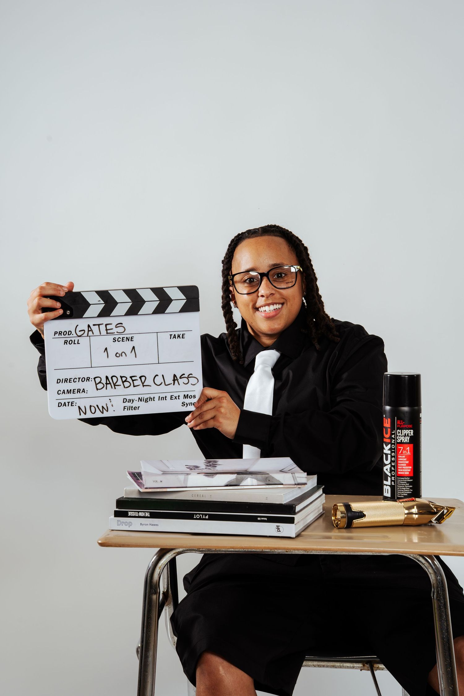 Smiling person holding film clapperboard reading Barber Class at desk with Black Ice spray.