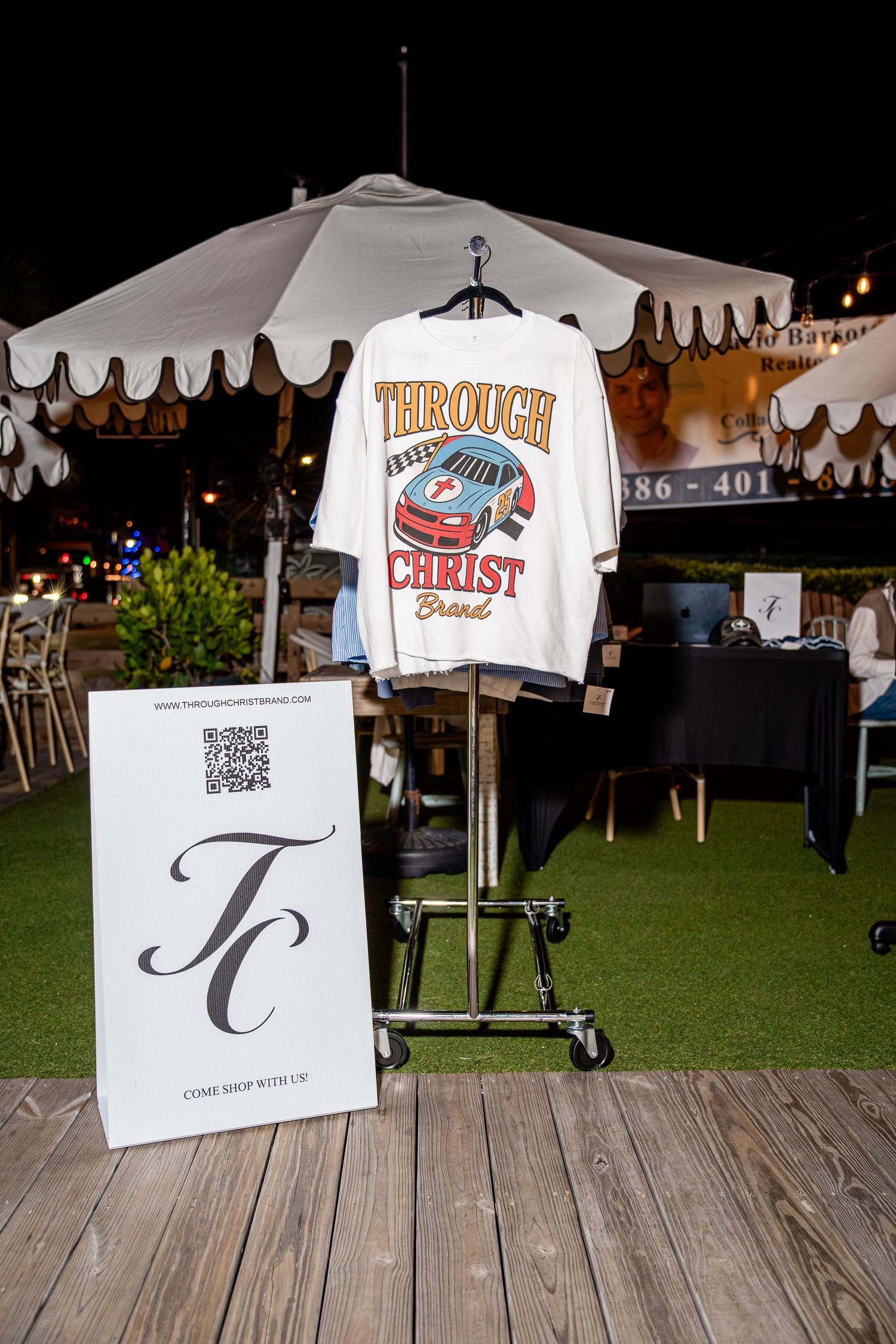Through Christ Brand racing graphic t-shirt displayed at outdoor night pop-up market.