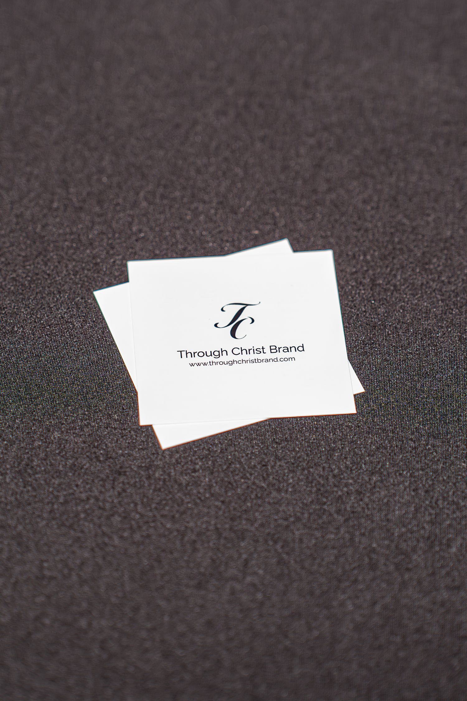 Through Christ Brand business cards with logo and website displayed on a dark surface.
