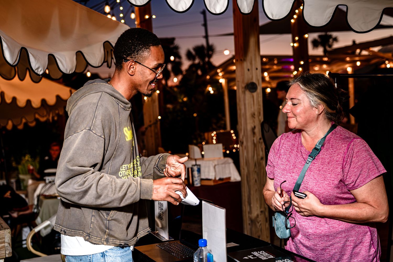 Young man interacting with a woman at an outdoor vendor booth during a nighttime event.