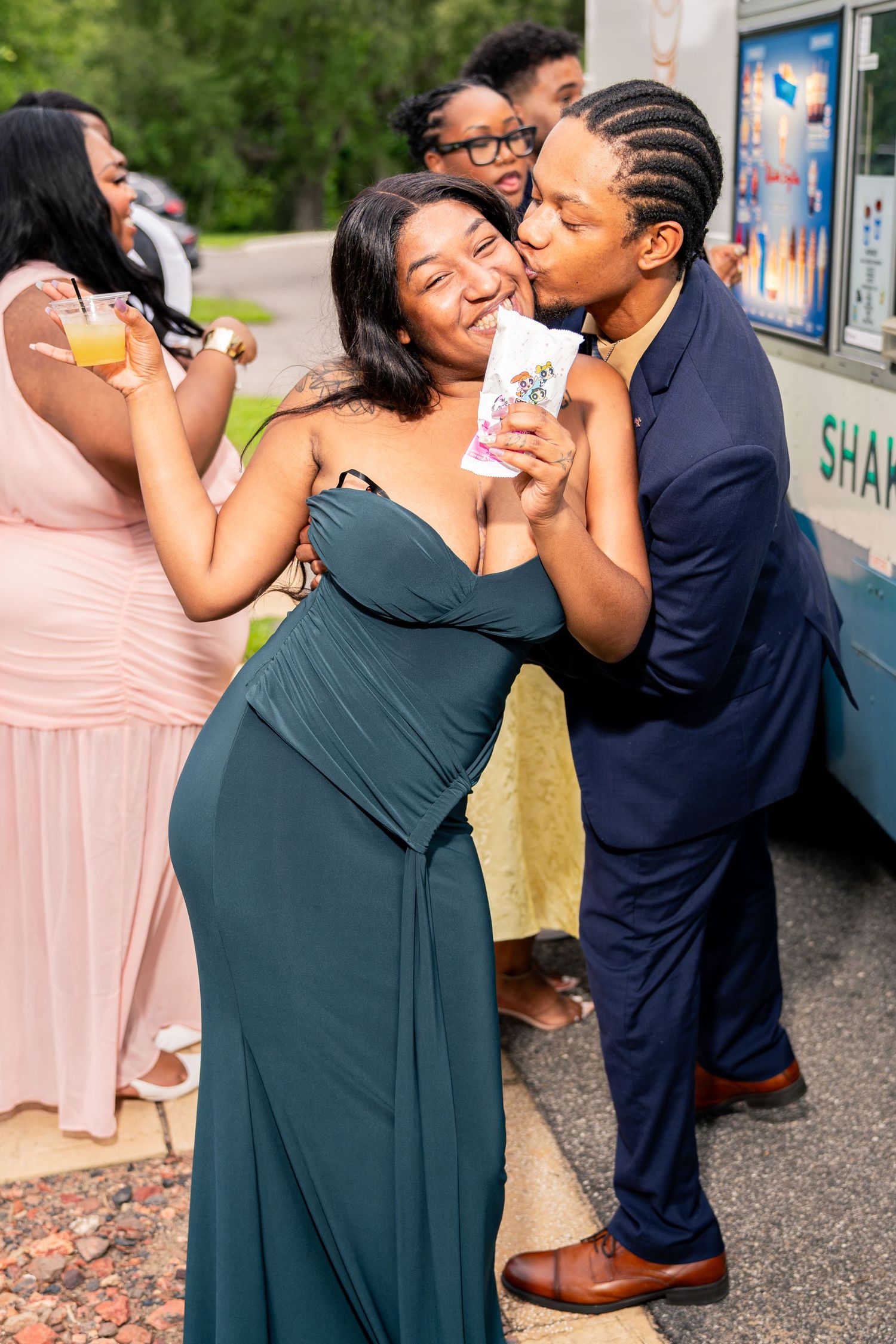 Wedding guests share a fun moment with shaved ice treats outside near a food truck during wedding celebration.