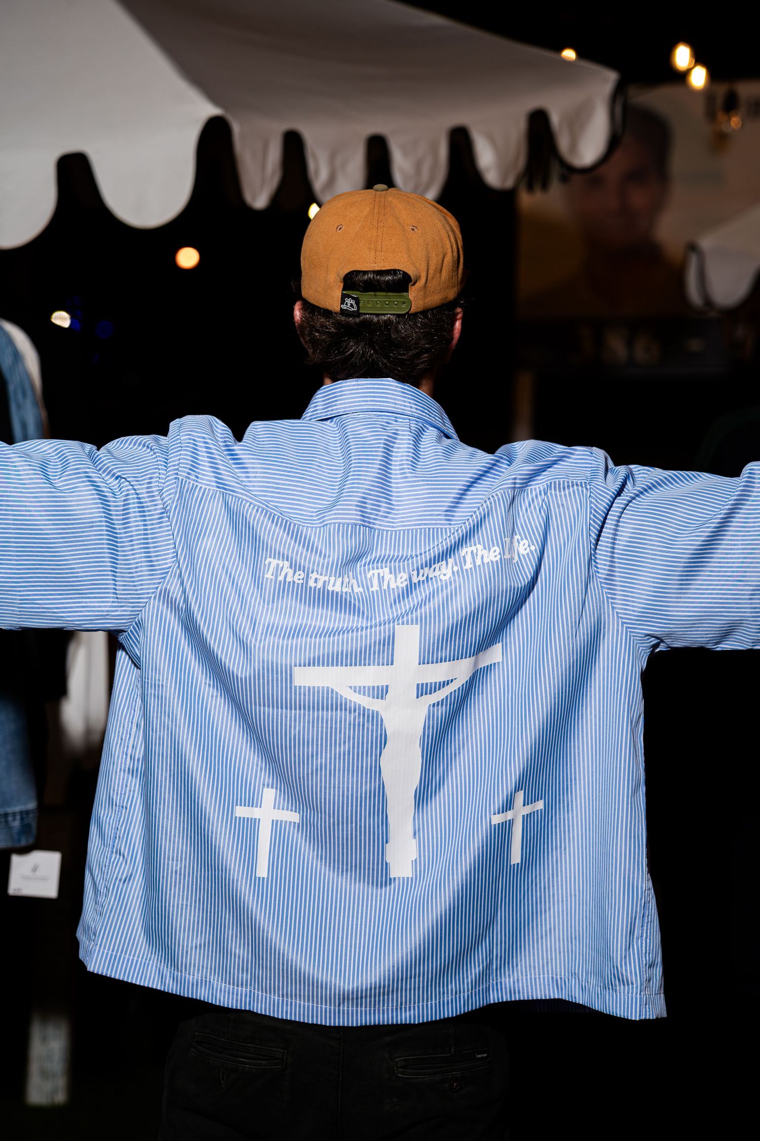 Back view of blue pinstripe shirt with crucifixion cross print and scripture text design.