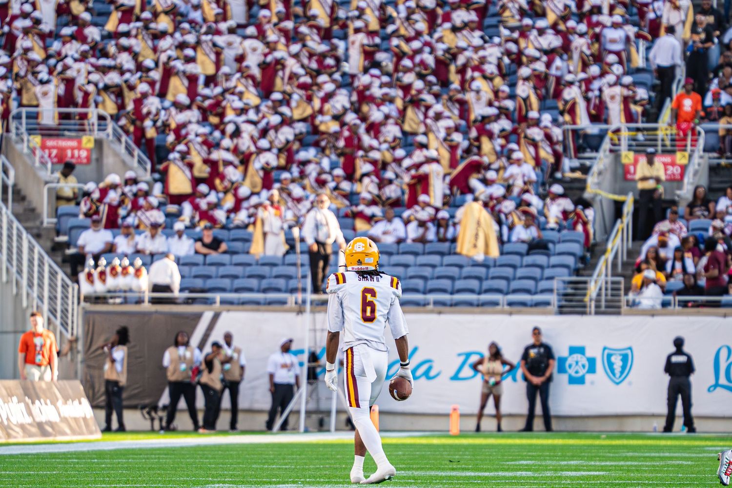 Football player #6 in white uniform stands on field before packed stadium crowd during college game.