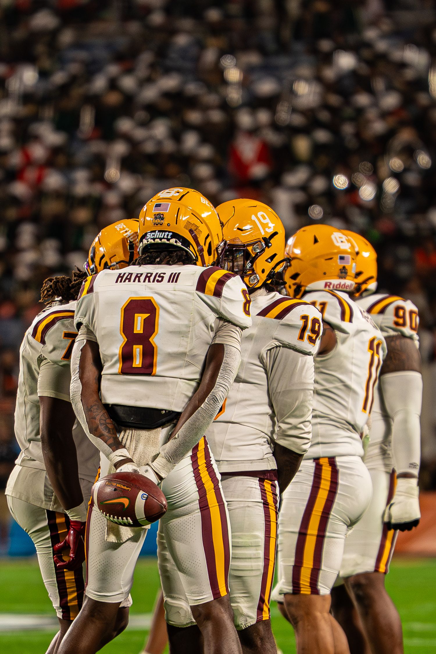 Bethune-Cookman football player Harris III #8 huddles with teammates during a night game.
