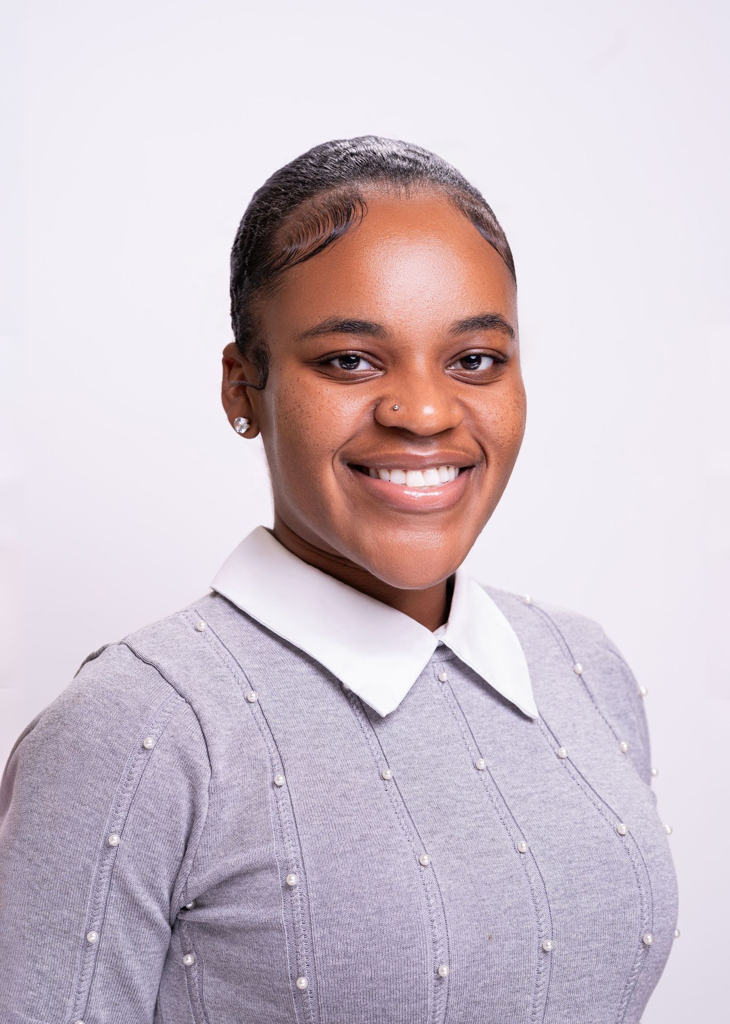 Smiling young woman in a gray knit sweater with white collar poses for a professional headshot photo.