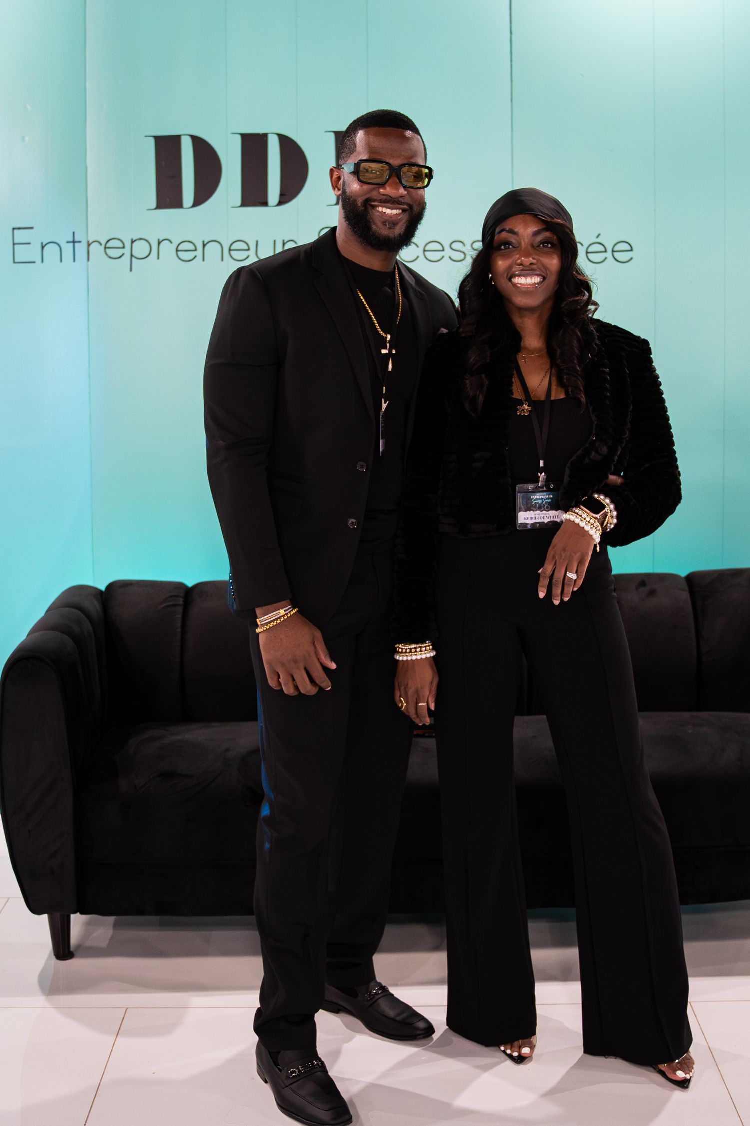 Man and woman in coordinating black outfits pose together at DDH Entrepreneur Success business conference event.