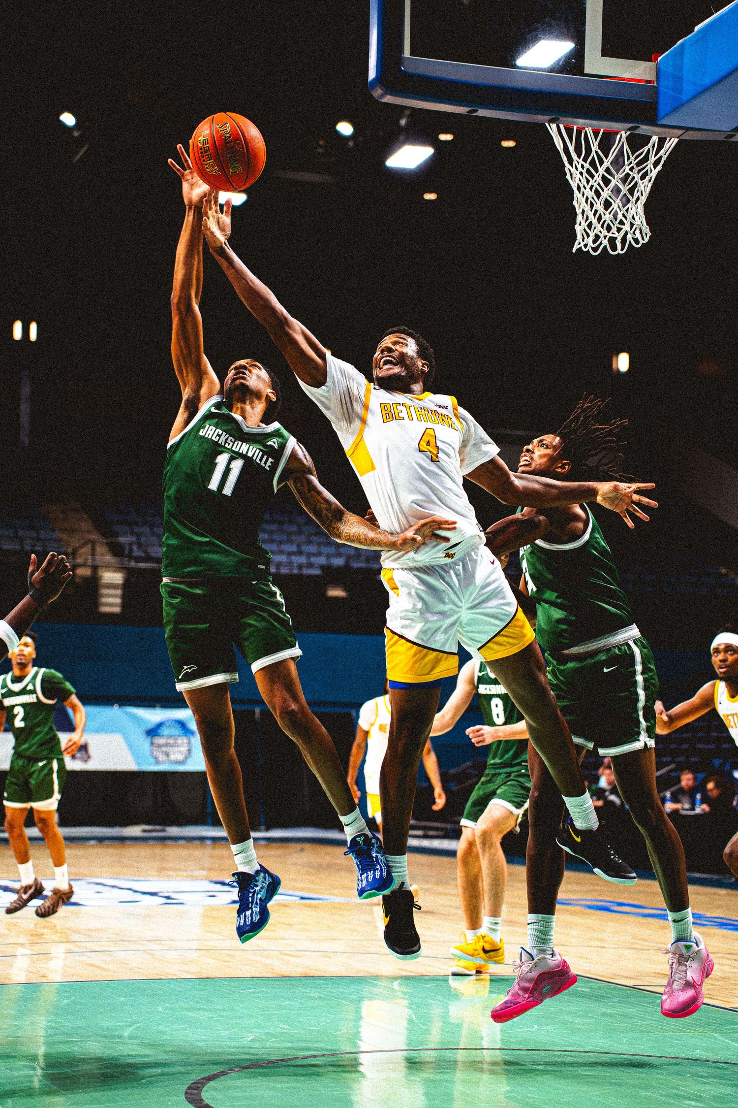 Bethune-Cookman player #4 battles Jacksonville University defenders for a rebound near the basket.