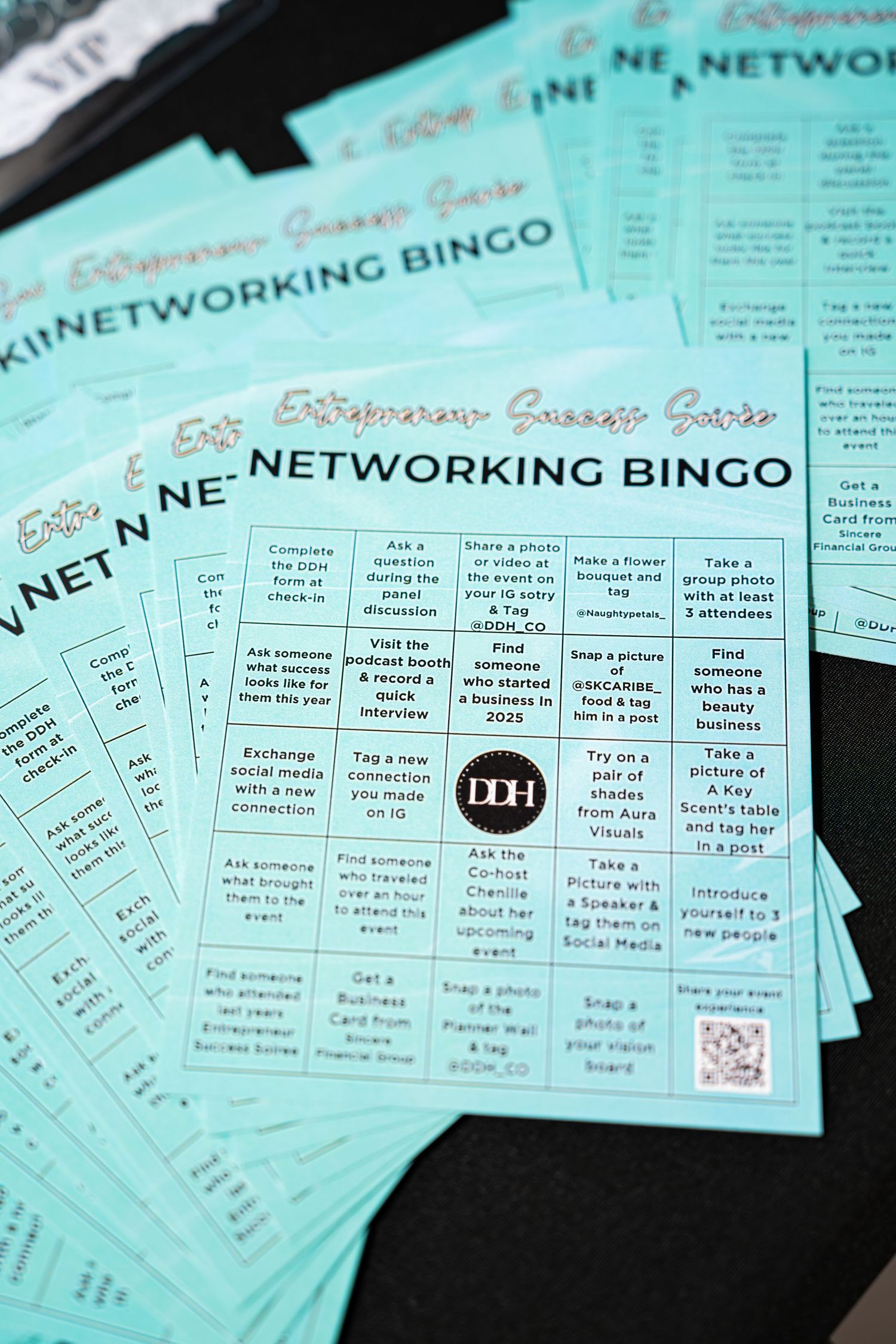 Teal Networking Bingo cards spread on a table for the Entrepreneur Success Soiree 2025 event.