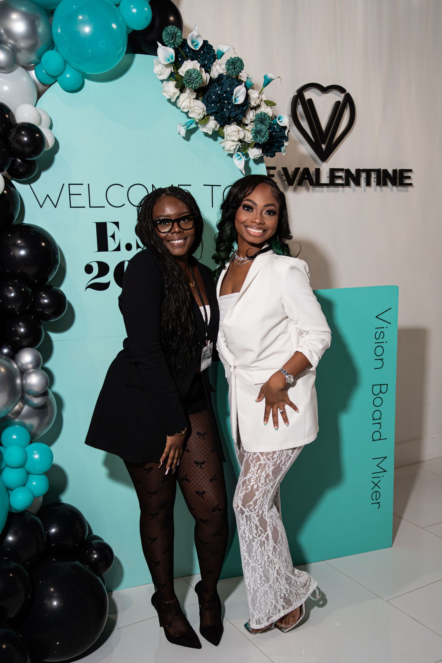 Two women pose at ESS 2026 Vision Board Mixer event with teal and black balloons.