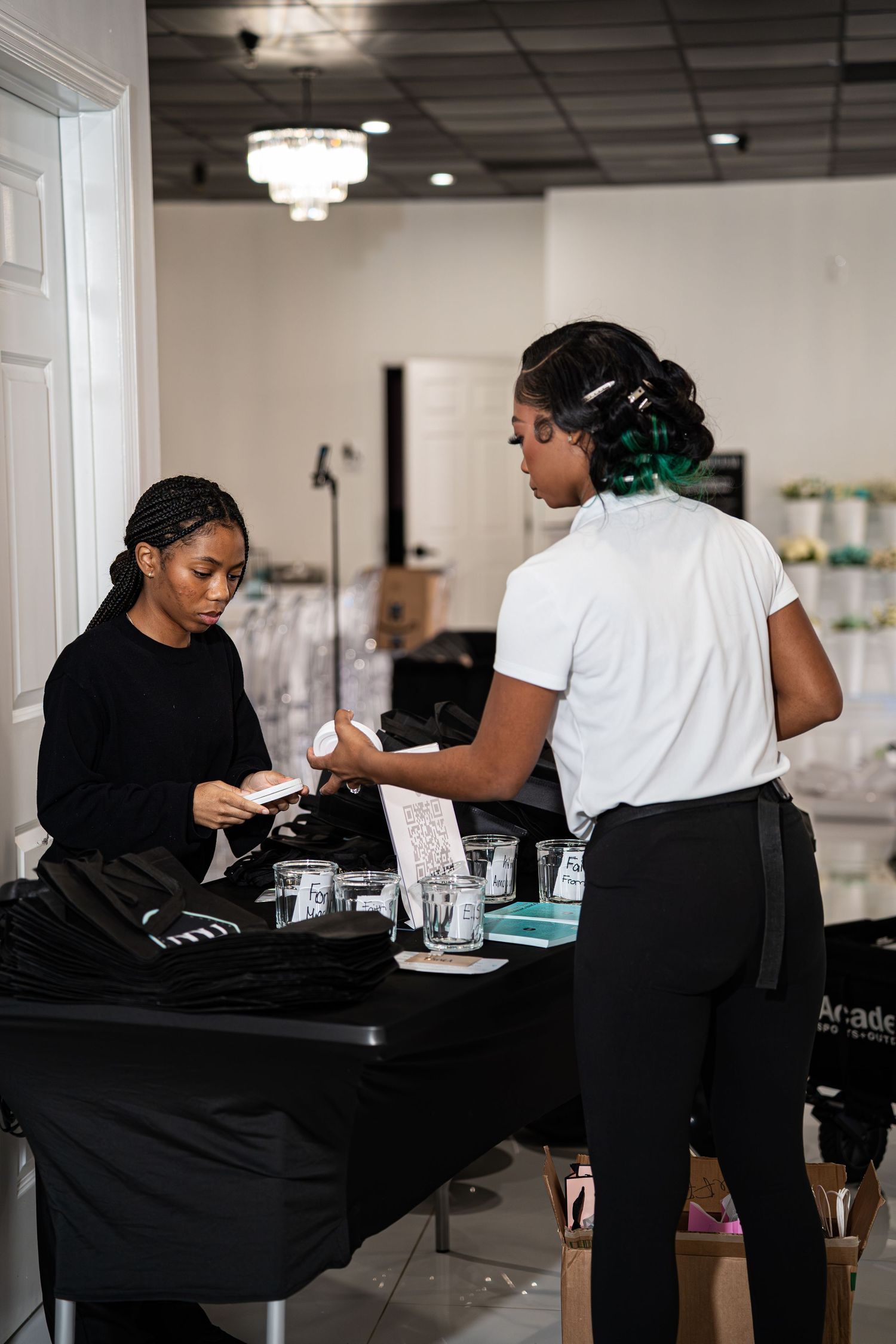 Two women handle registration materials at a check-in table during a professional networking event.