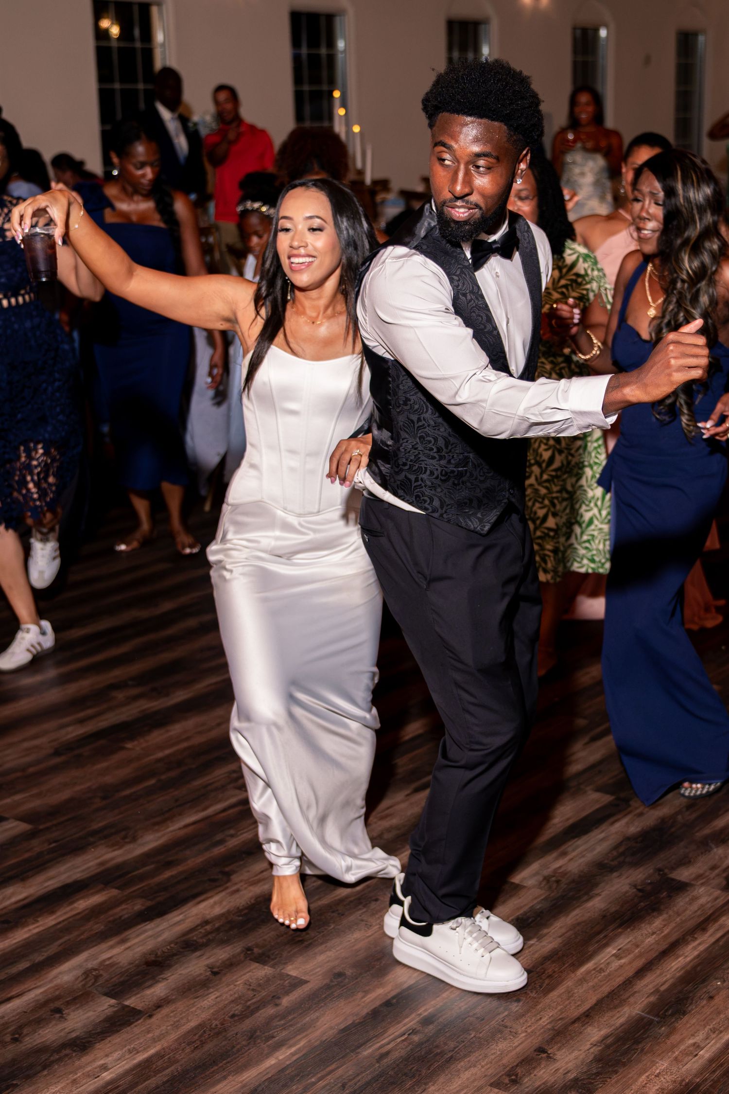 Couple dancing together on crowded wedding reception dance floor.