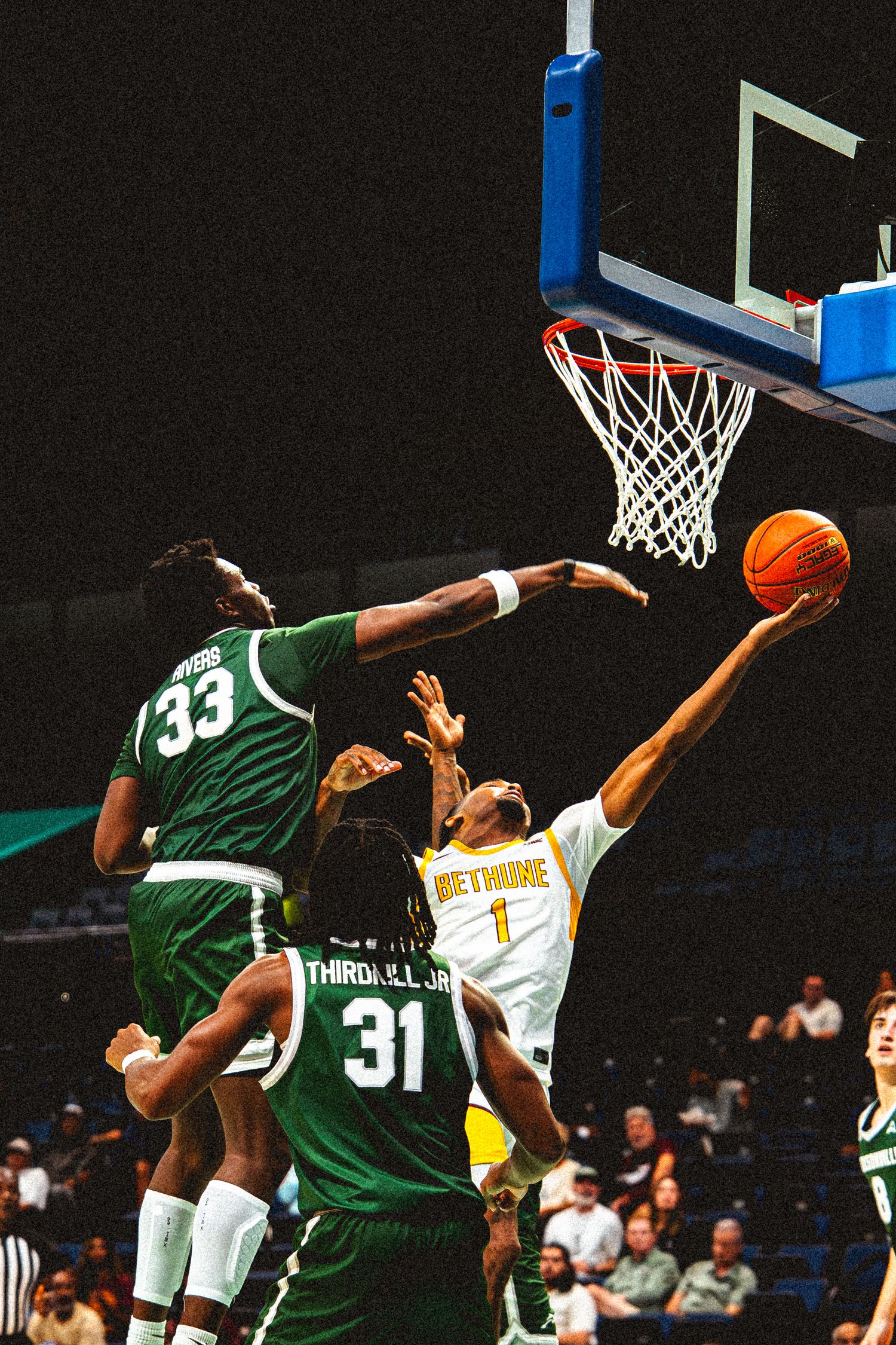 Bethune-Cookman player number 1 attempts layup against Jacksonville defenders number 33 and 31.