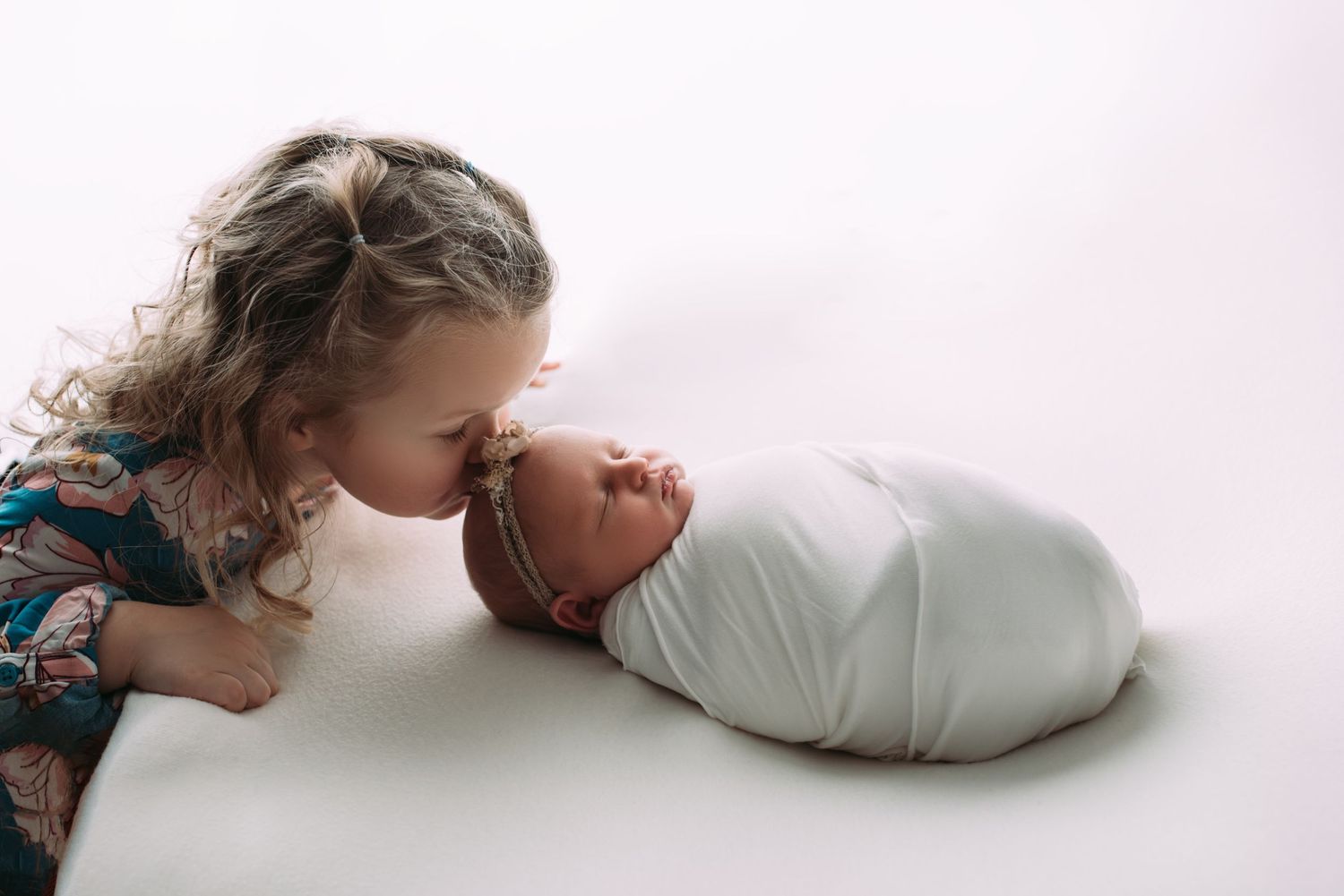 Sister kissing a newborn baby girl during a newborn session in Woodbury MN