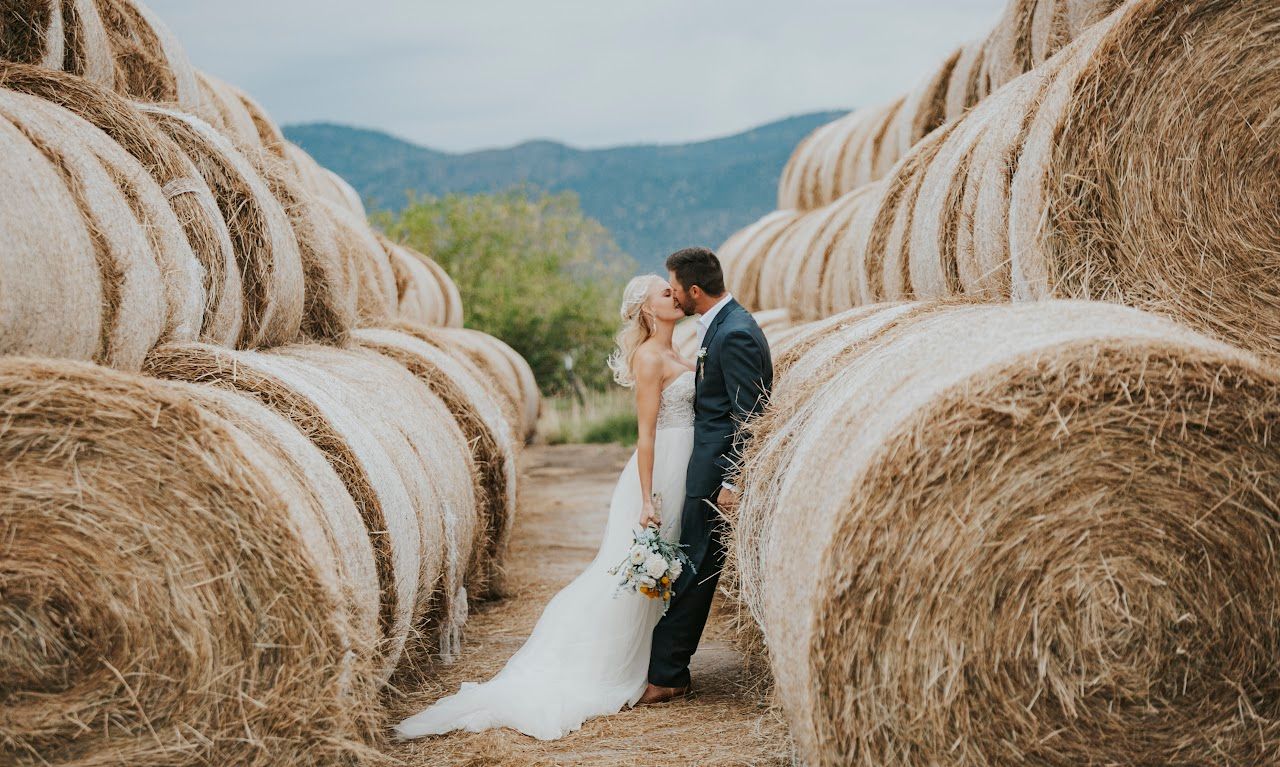 Portrait of bride and groom kissing and surrounded by hay bales