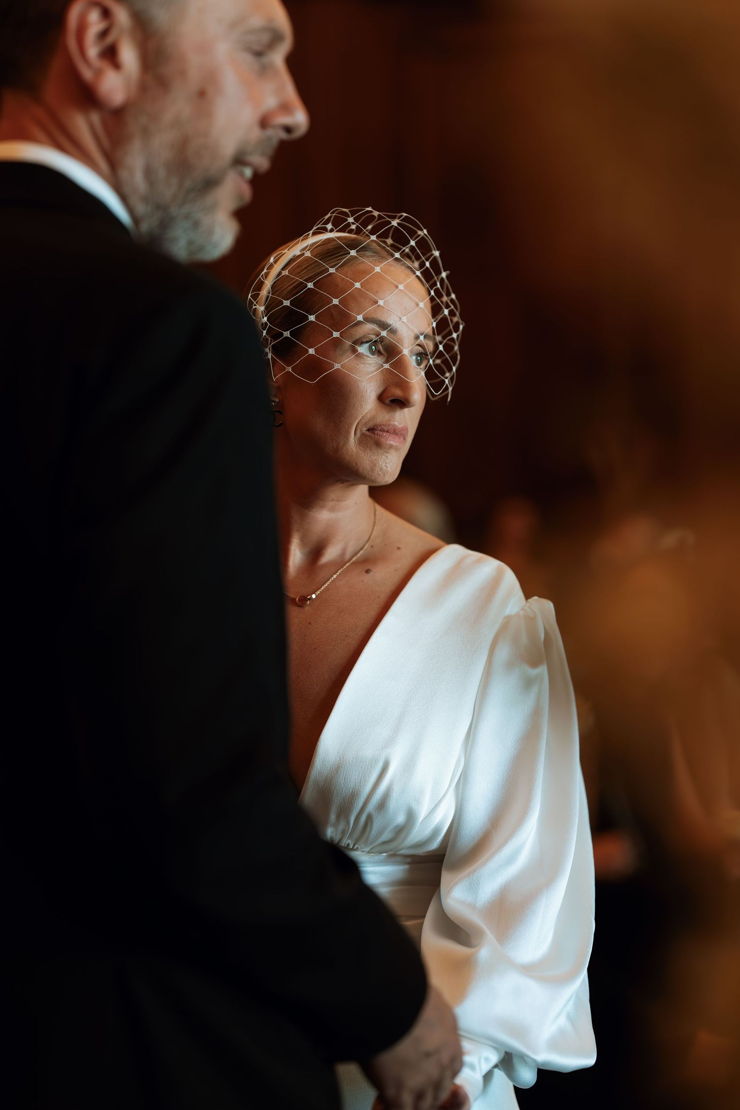 A vintage-style wedding photo featuring an elegant white dress and delicate birdcage veil.
