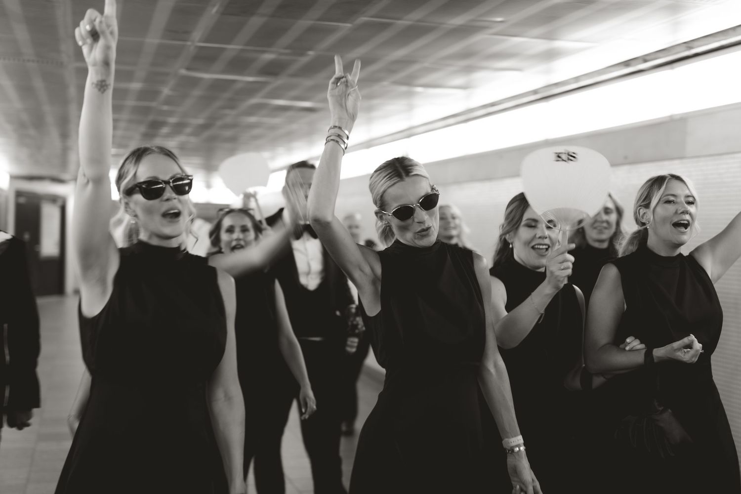 Group of women in black dresses dancing joyfully together at a celebration.