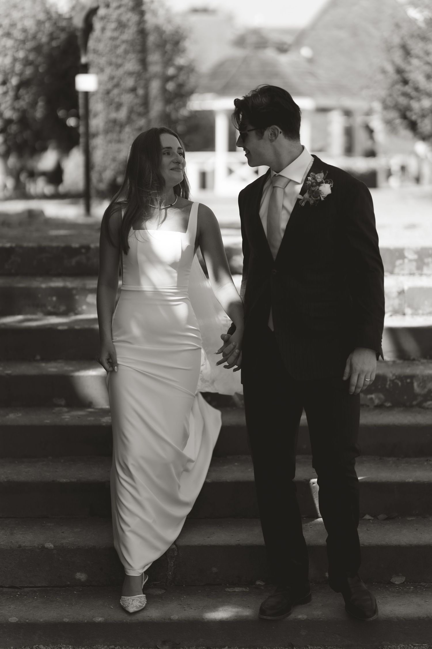 Black and white photo of a romantic wedding couple posing together on stone steps outdoors.