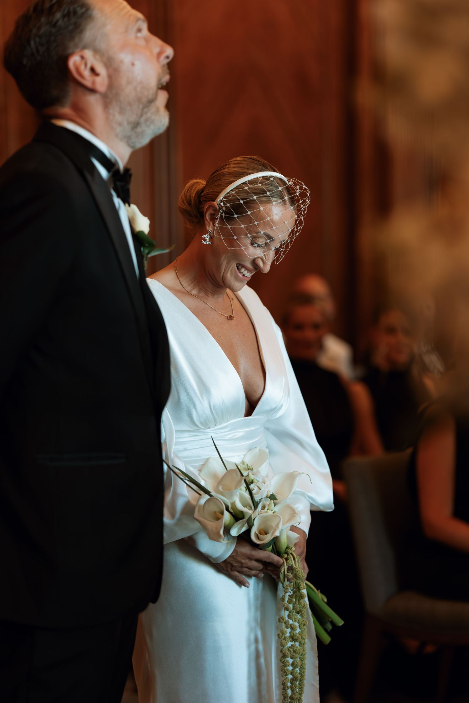 A bride and groom share a candid moment during their wedding ceremony, with the bride wearing an elegant white dress.