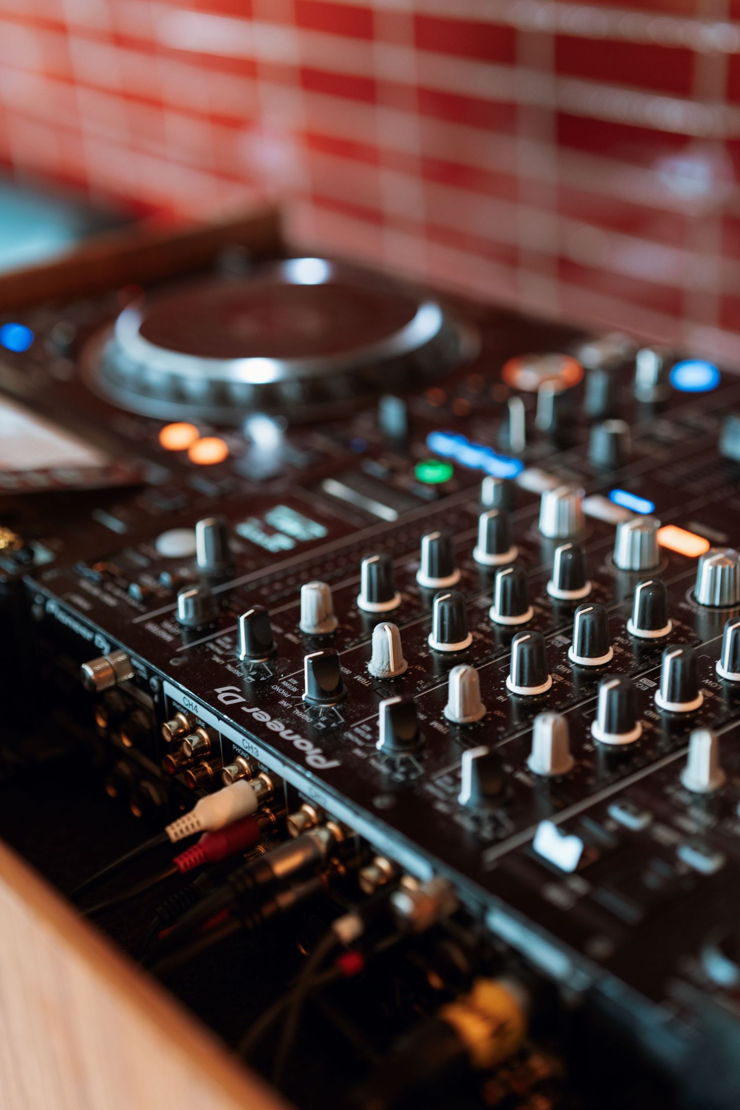 Close-up of a professional DJ mixer with knobs and controls in moody lighting.