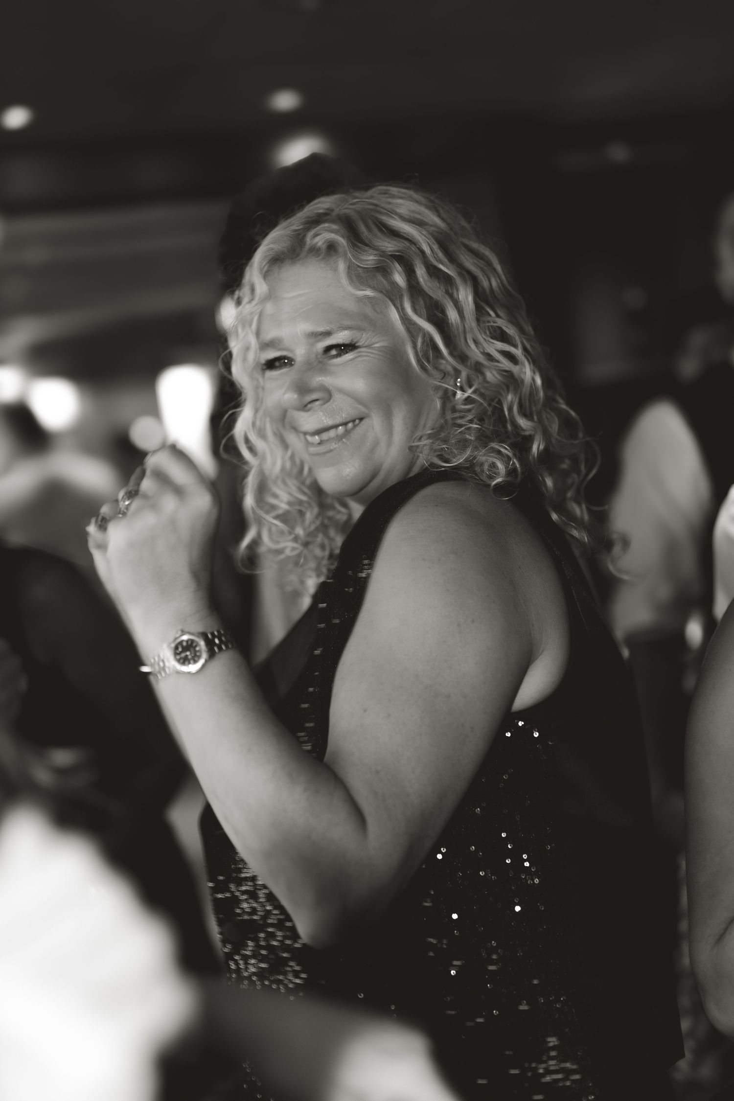 Black and white portrait of party guest dancing joyfully in sequined dress.